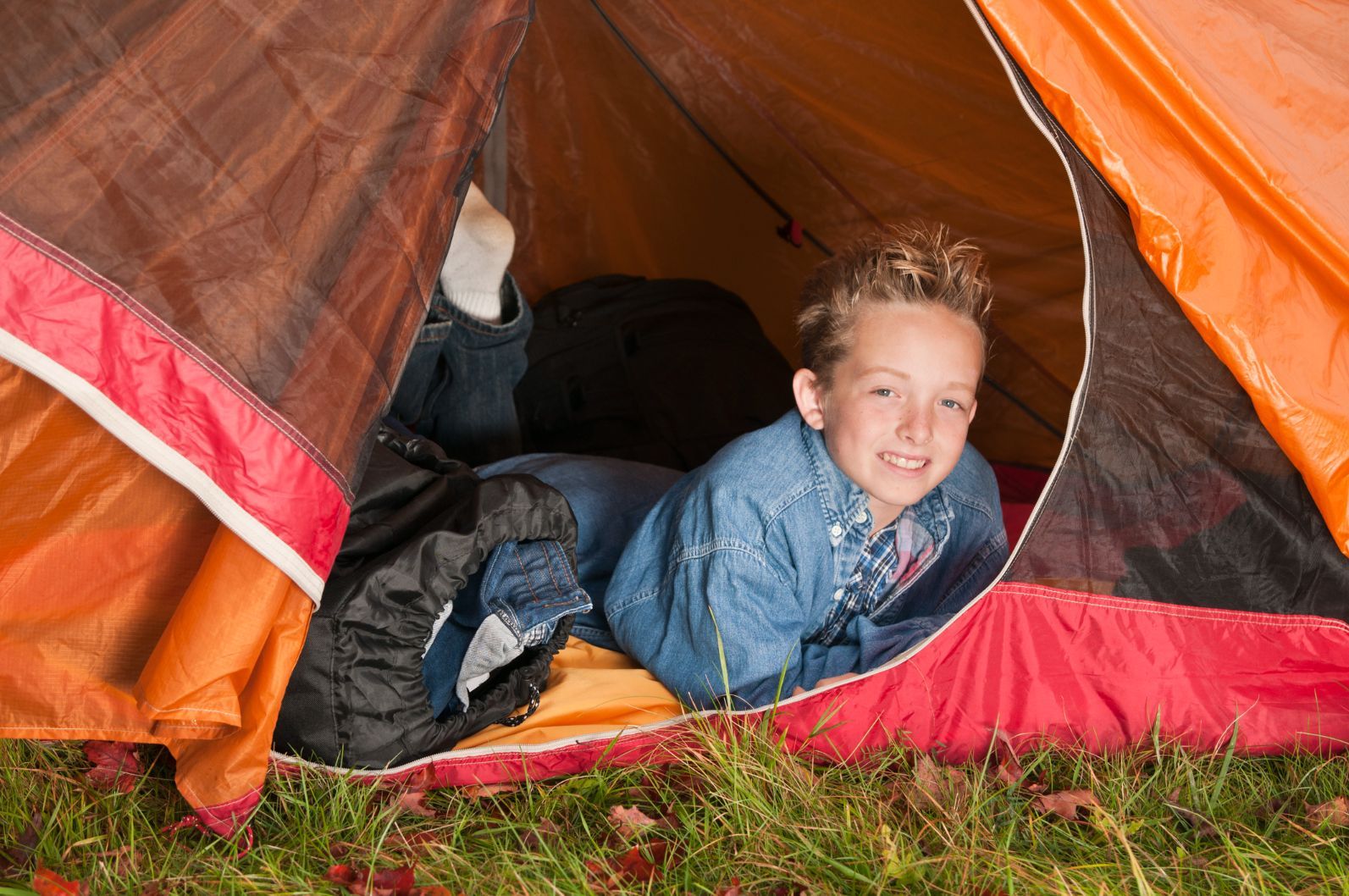 A child in a red tent, camping with family.