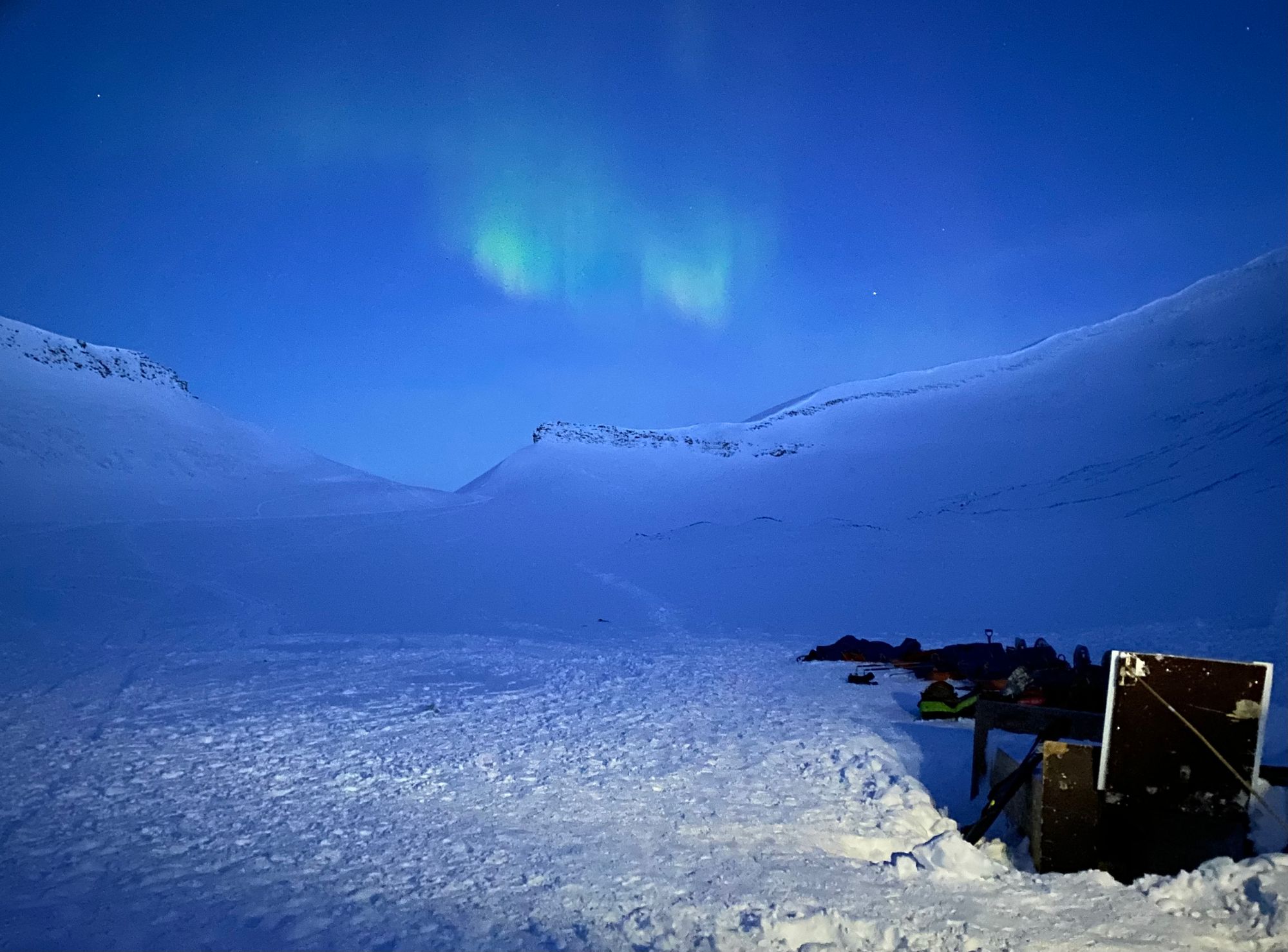 Aurora above a snowy landscape, with a hatch leading undergroud