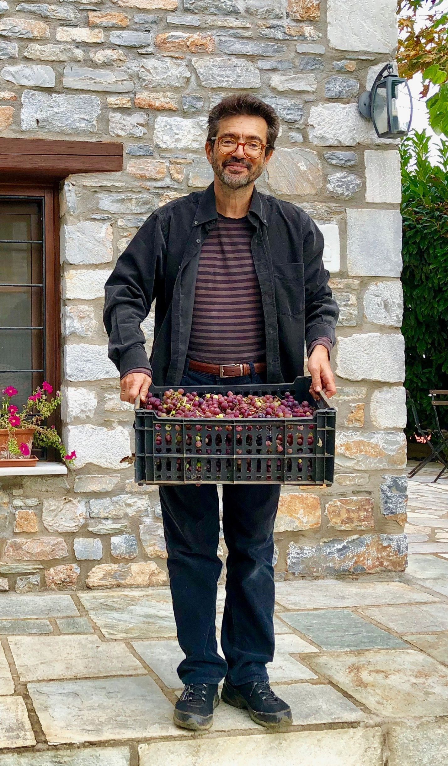 Man holding a crate of grapes in Greece.