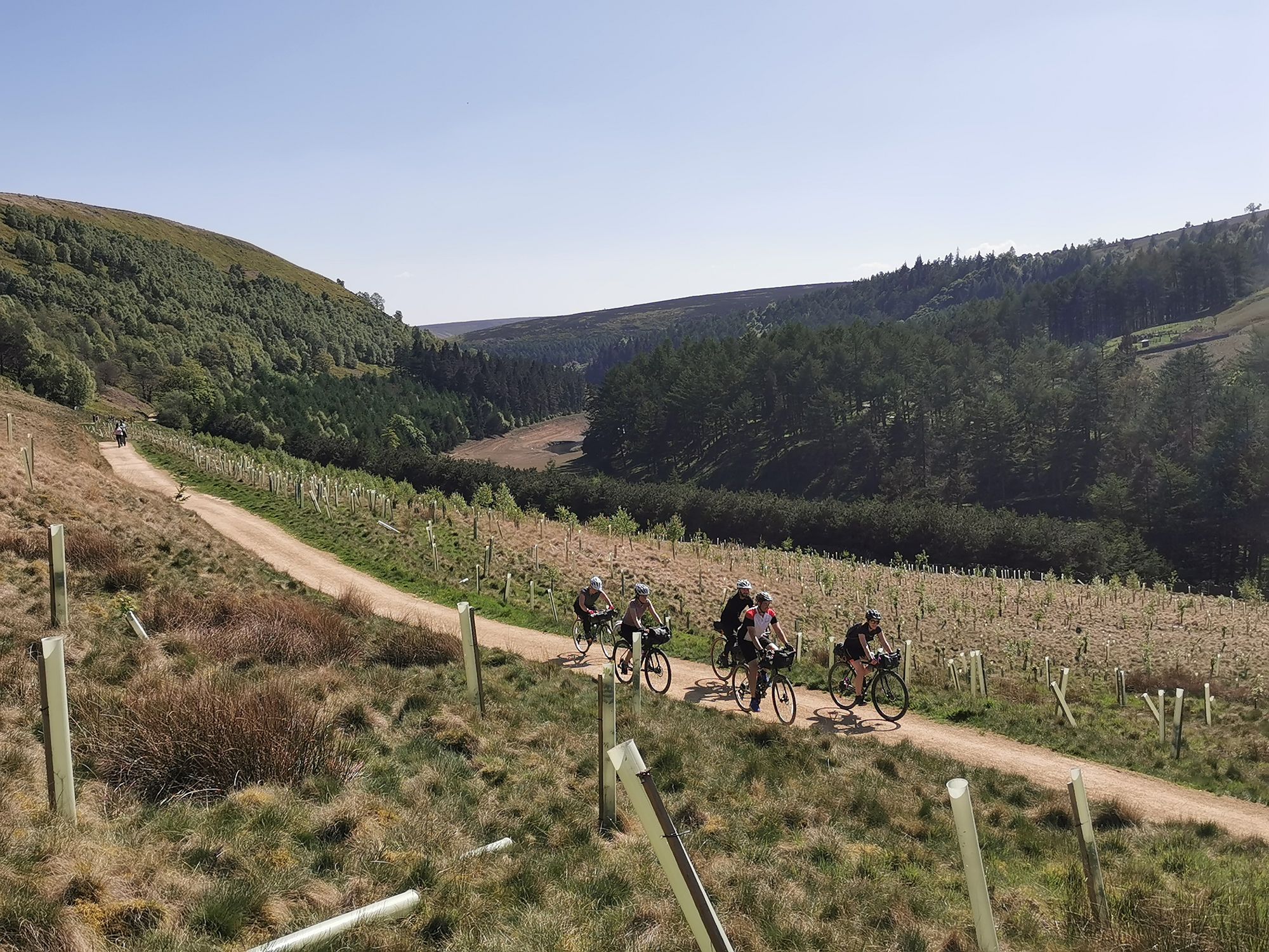 Five cyclists on a track pedalling through the Peak District.