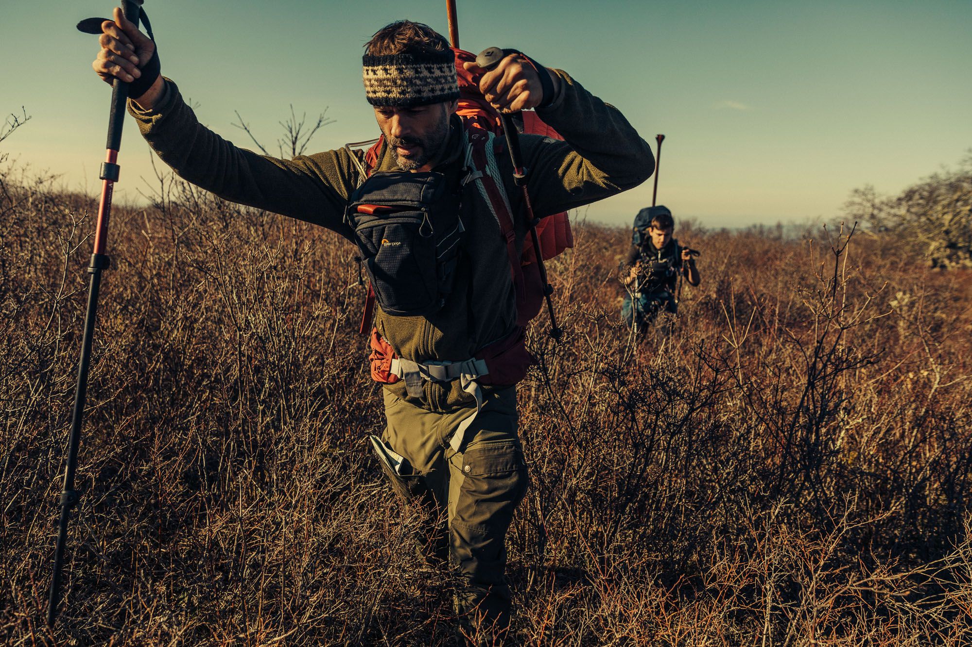 Two hikers making their way through scrubland.