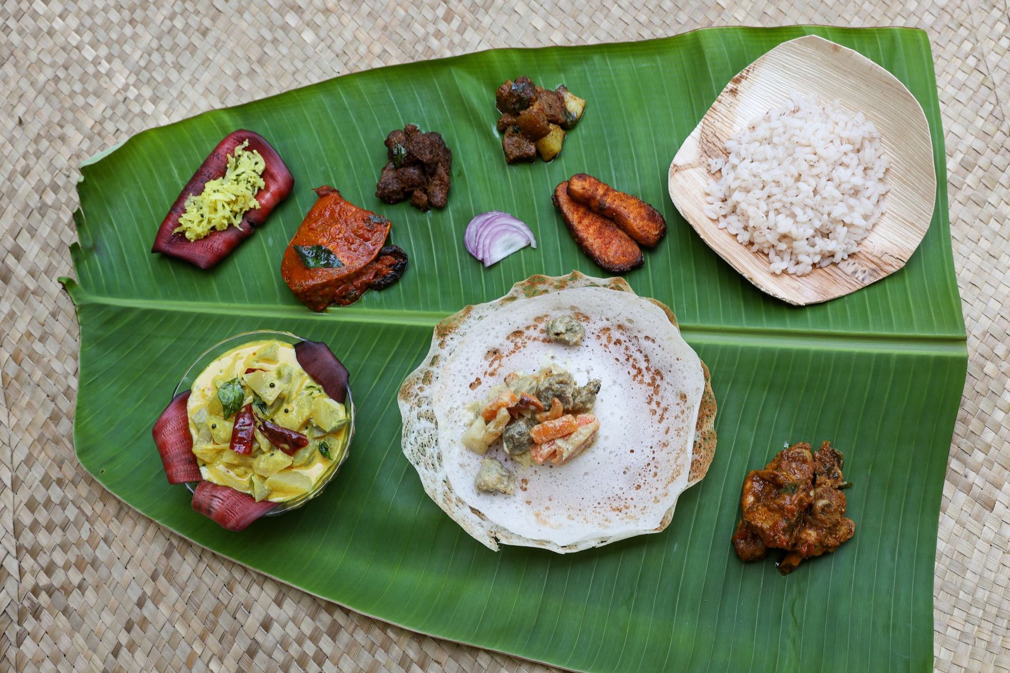 Keralan celebration meal of fish curry, appams, ishtu and more served on a banana leaf