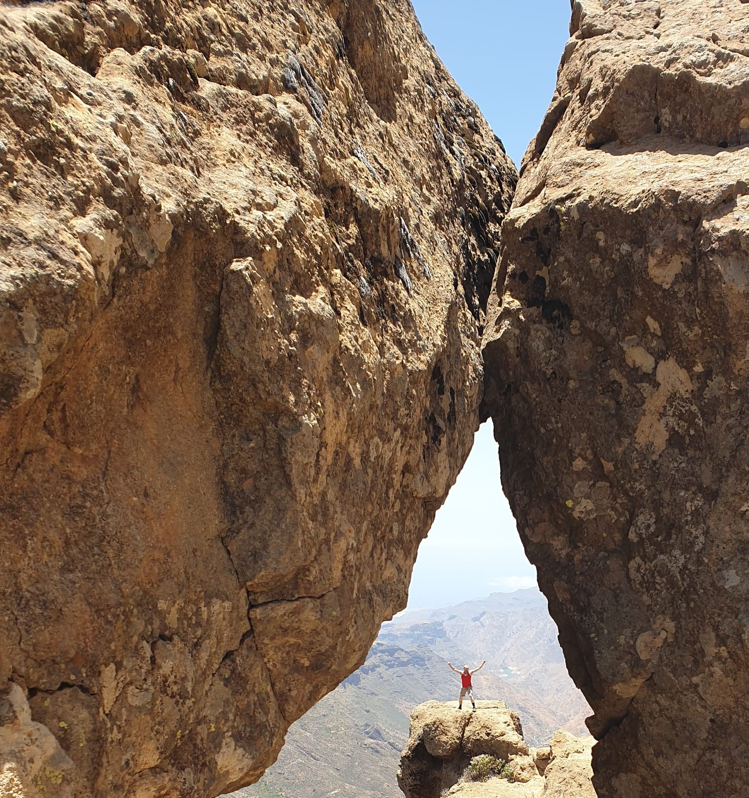 Male hiker seen through the gap in two rocks, Gran Canaria