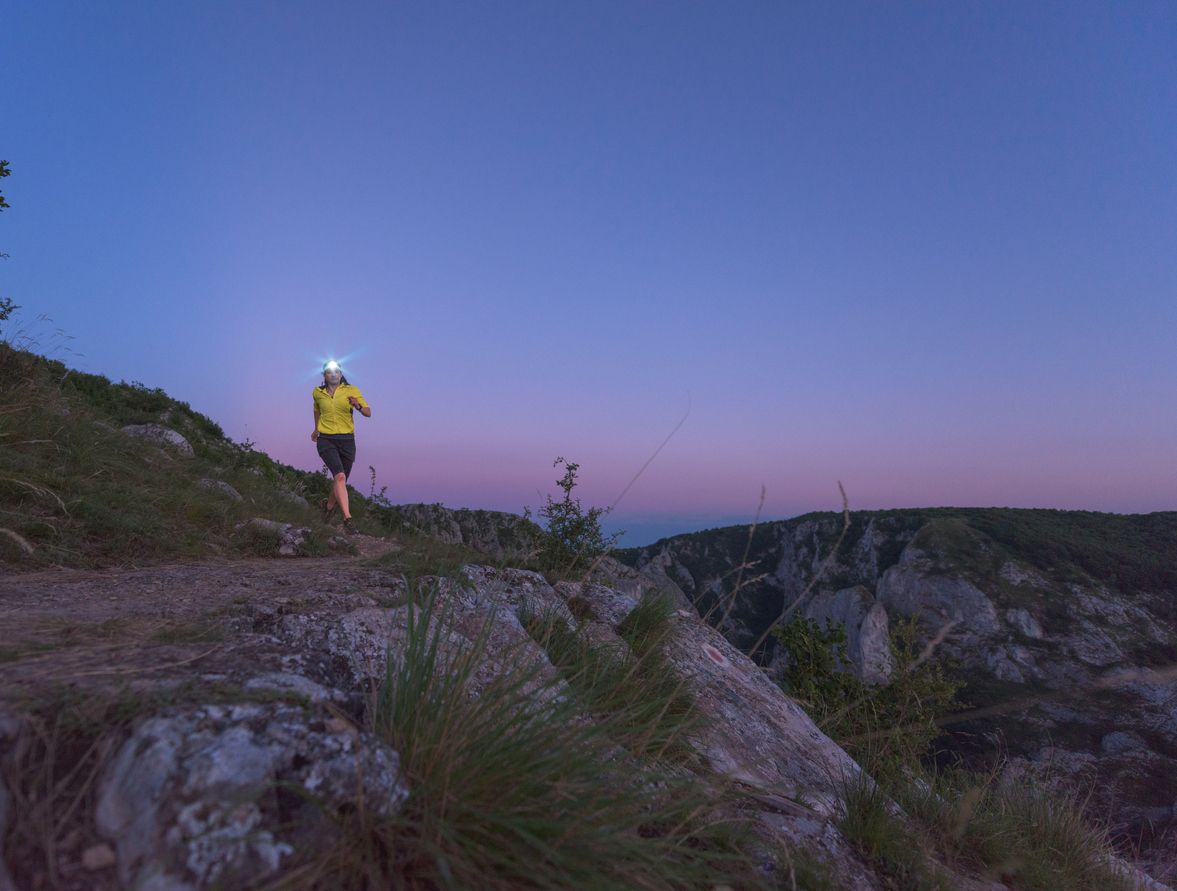 A runner on the trails at dusk, wearing a head torch