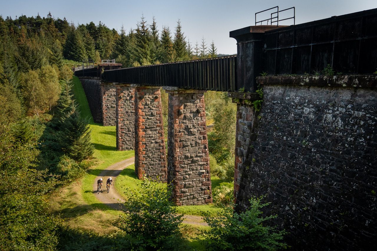 Two gravel cyclists pass beneath the scenic Loch Katrine Aqueduct on the new waymarked trails around Aberfoyle. Photo: Stu Thompson