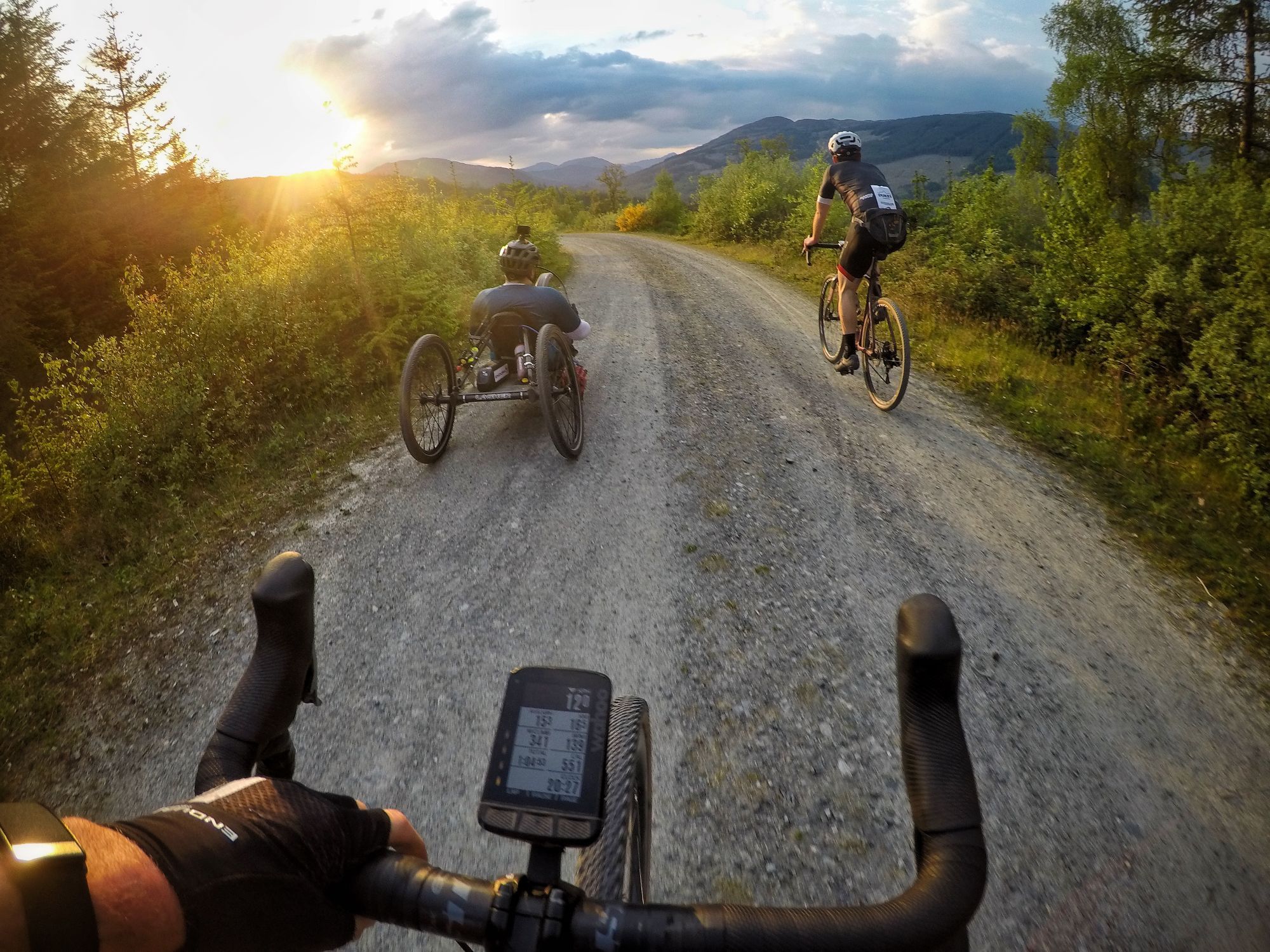 Three cyclists on a gravel trail in Aberfoyle, Scotland, one using a specially adapted bike.
