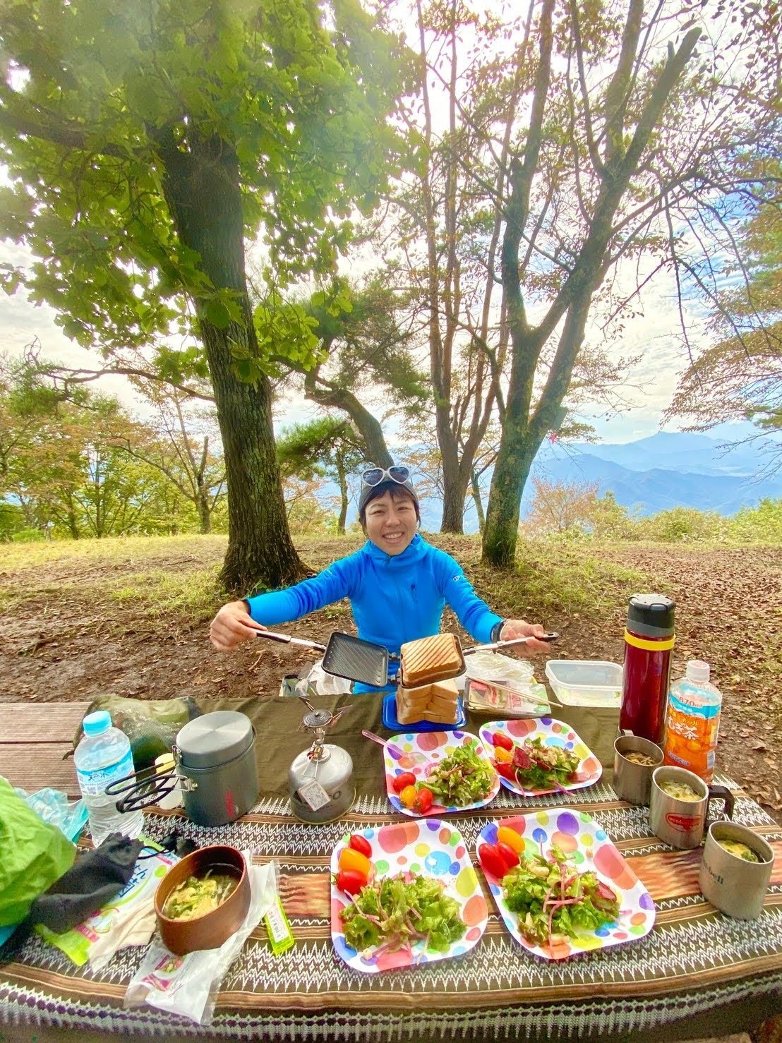 A Japanese hiking guide preparing a lunch of salad, toasted sandwiches and soup.
