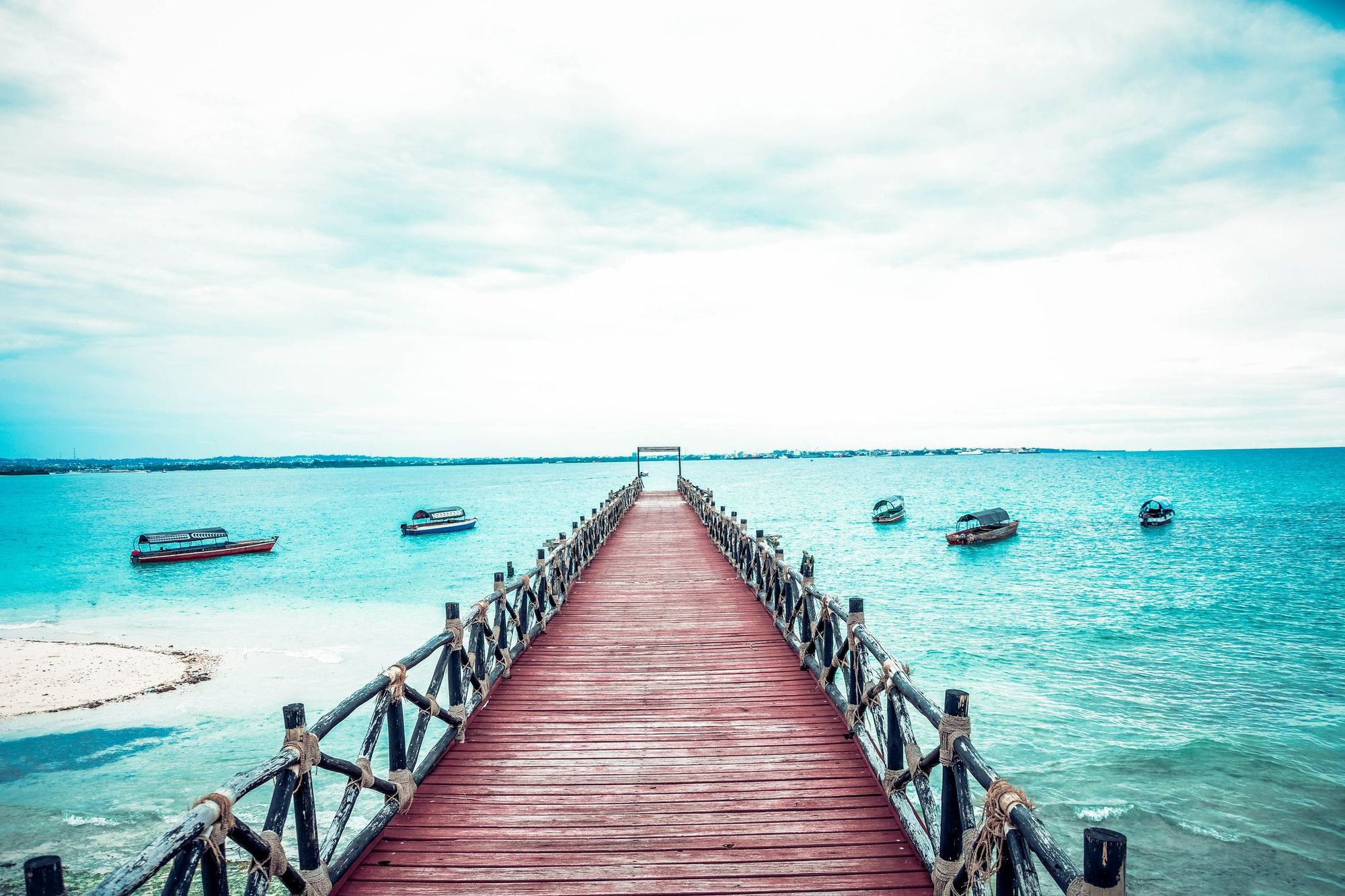 Dhows anchored offshore at Prison Island, Zanzibar - a wooden pier stretches into the ocean.