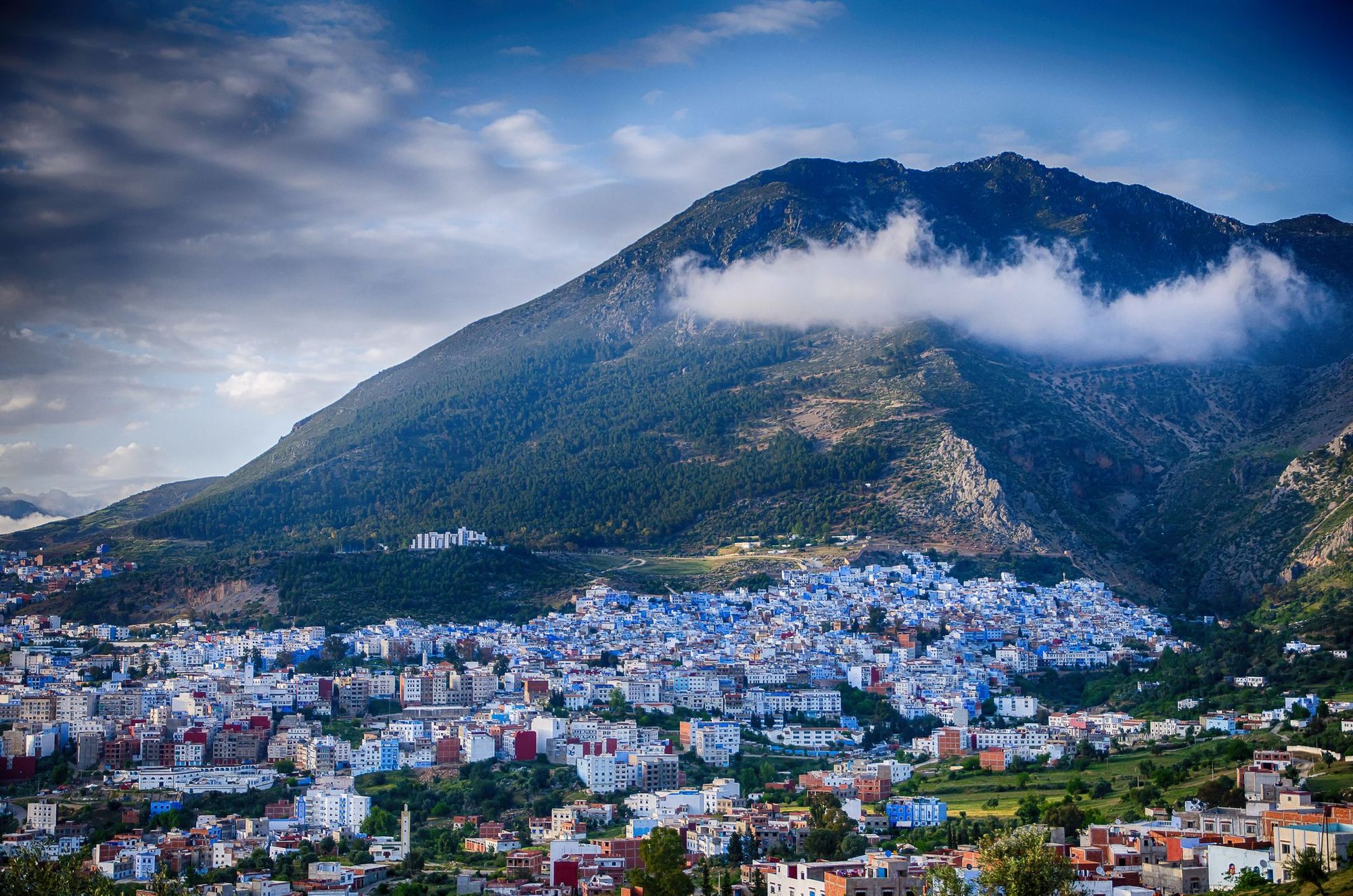 The blue houses of Chefchaouen in Morocco, with an imposing mountain behind them.