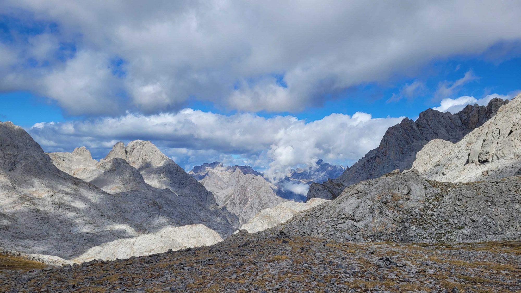 Jagged, grey limestone mountains with clouds and blue sky above in the Picos de Europa, Cantabria, Spain