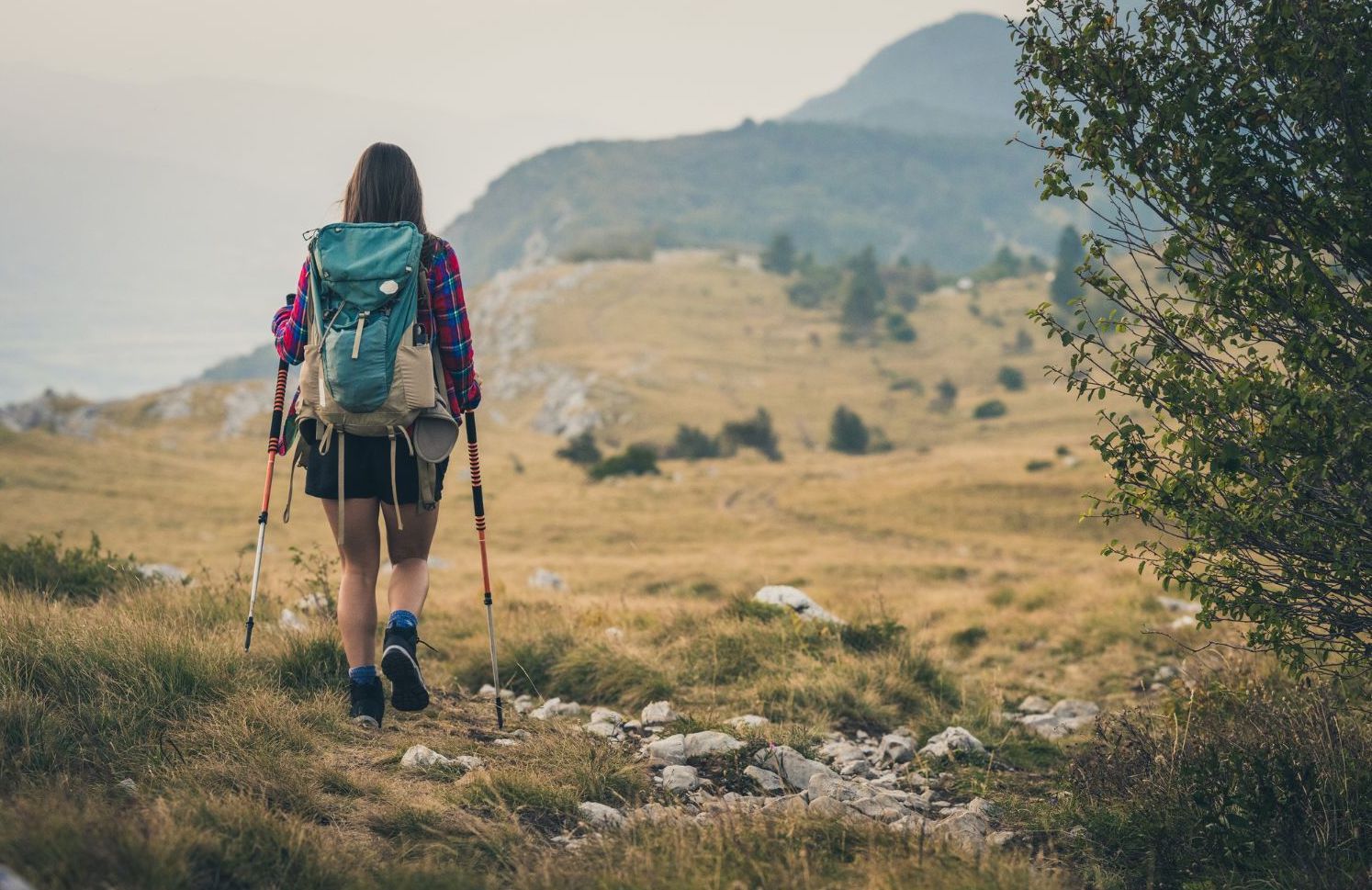 A woman hiking up a mountain, with a pack and walking poles, which take a substantial amount of force off the lower limbs. Photo: Getty
