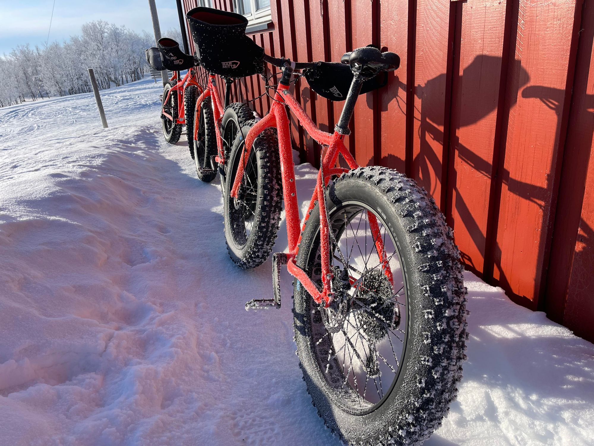 Fat bikes leaning against a red building in the snowy Arctic