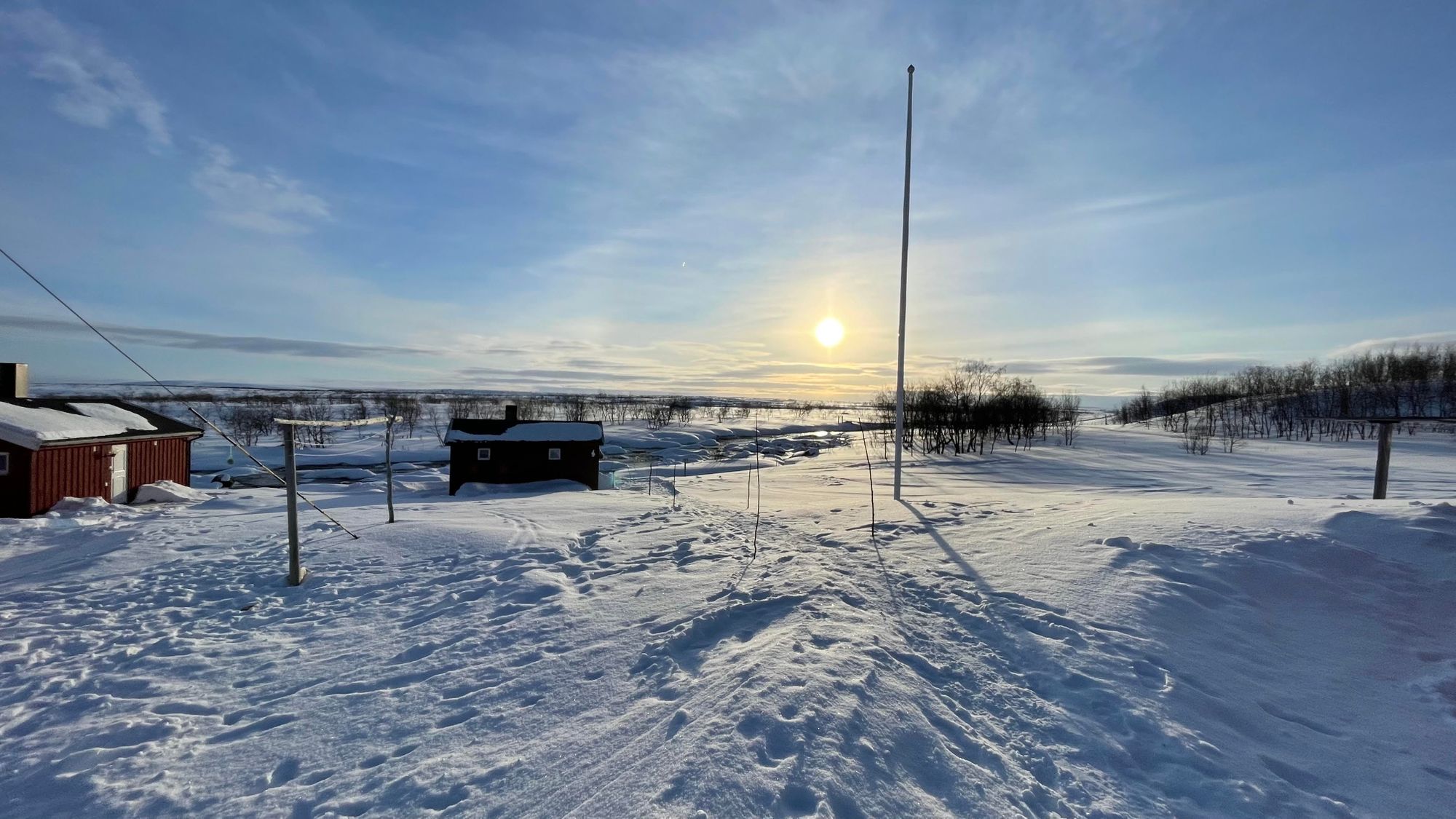 A snow covered Arctic landscape with the sun low in the sky