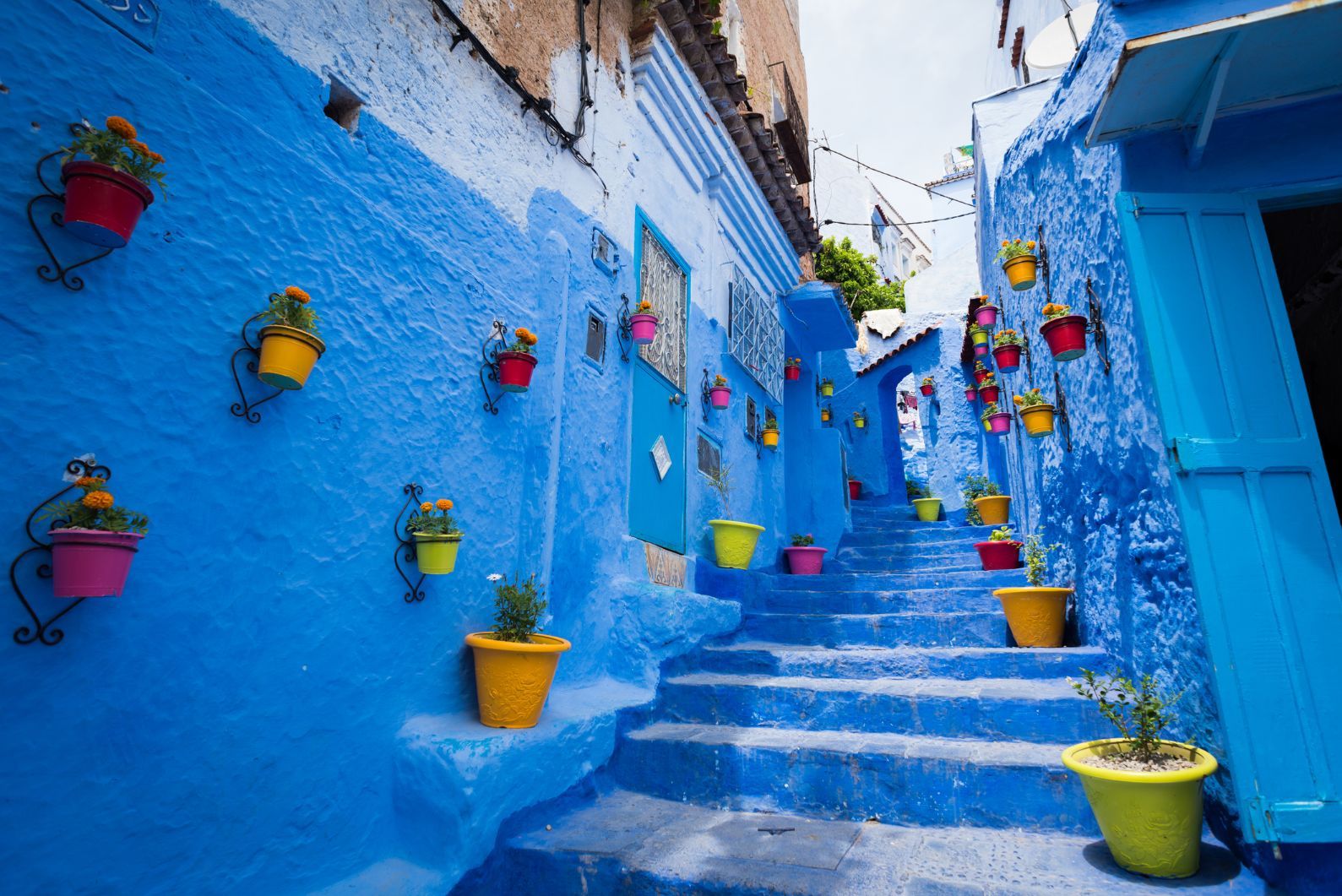 A blue passageway through the old town of Chefchaouen, brightened up with flower pots. Photo: Getty