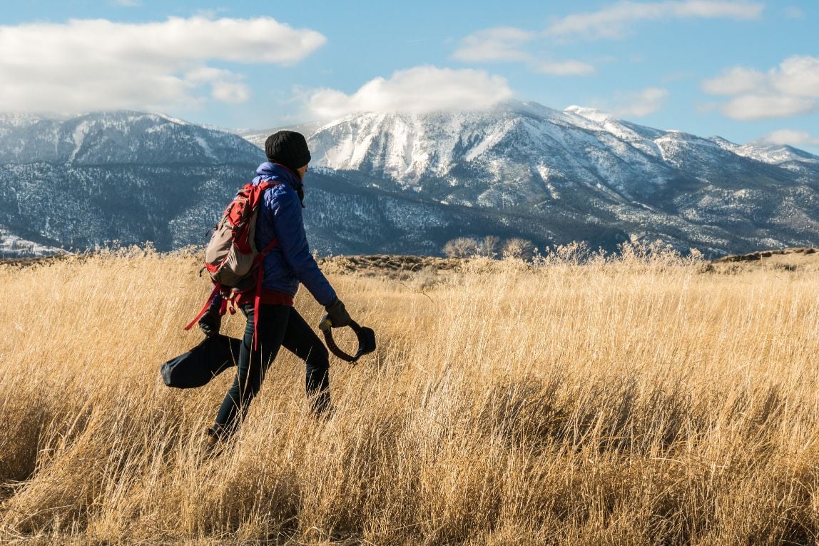 The ecologist Dr. Rae Wynn-Grant wonders through a field, beneath snowy mountains.