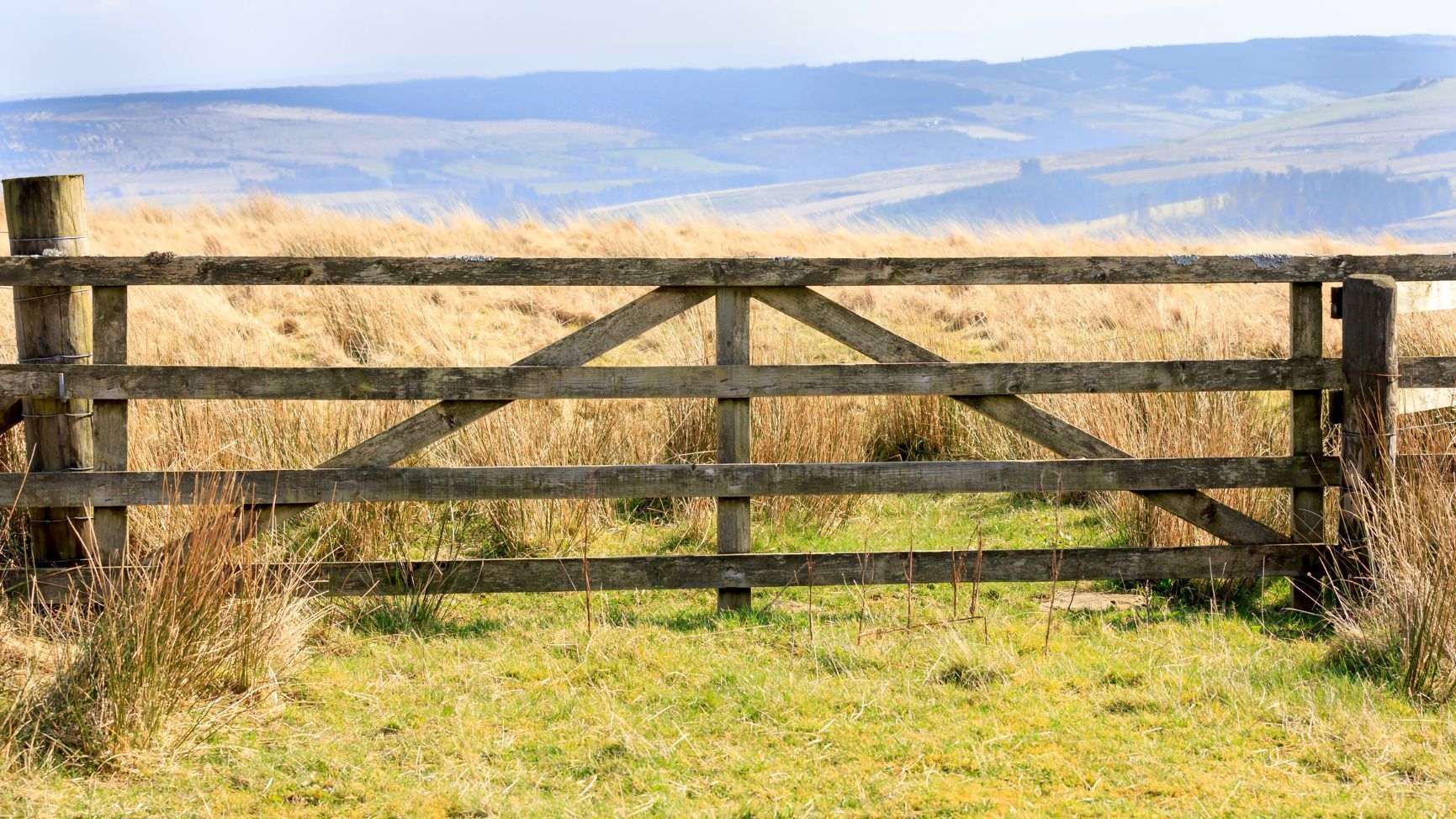 A wooden gate on Langholm Moore, looking out towards with mist covered hills of Cumbria in England.