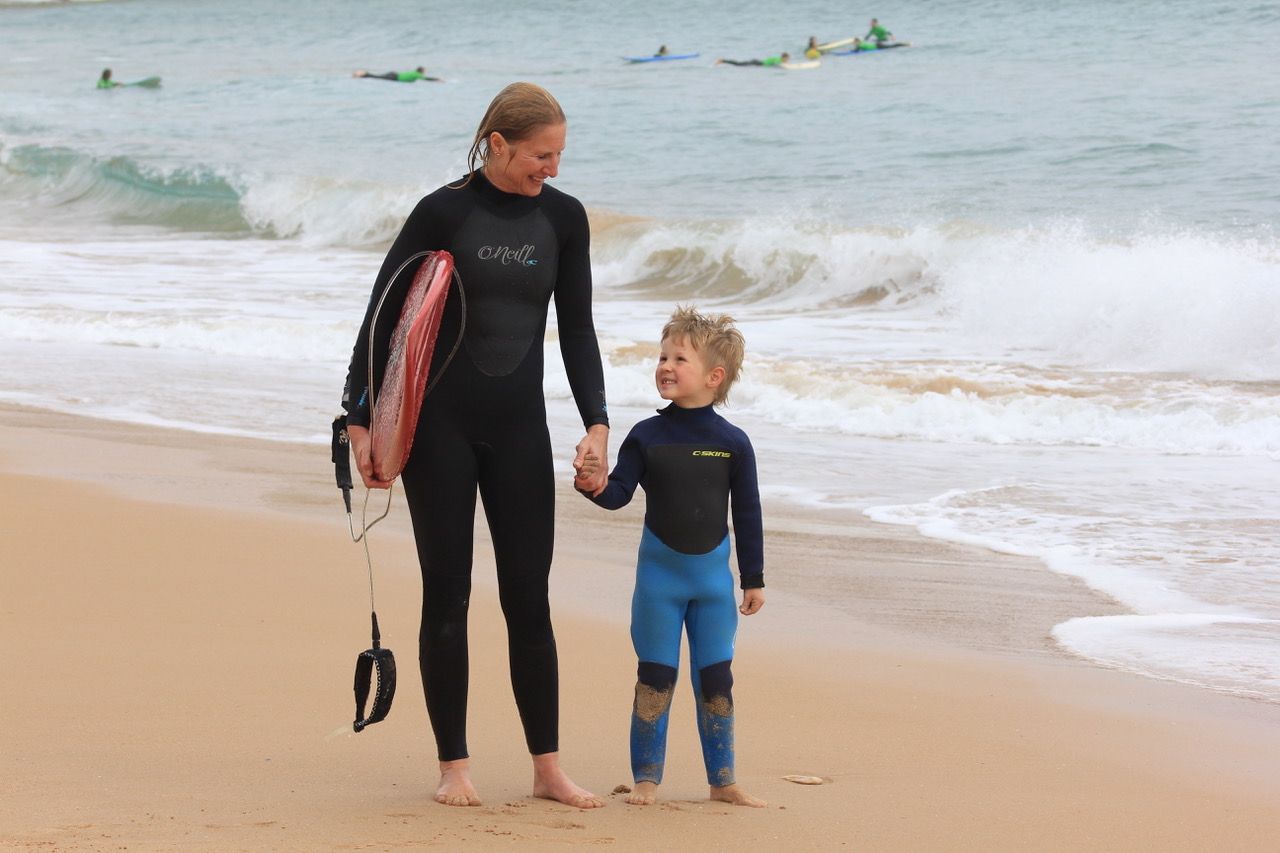 A female surfer with her child on the beach