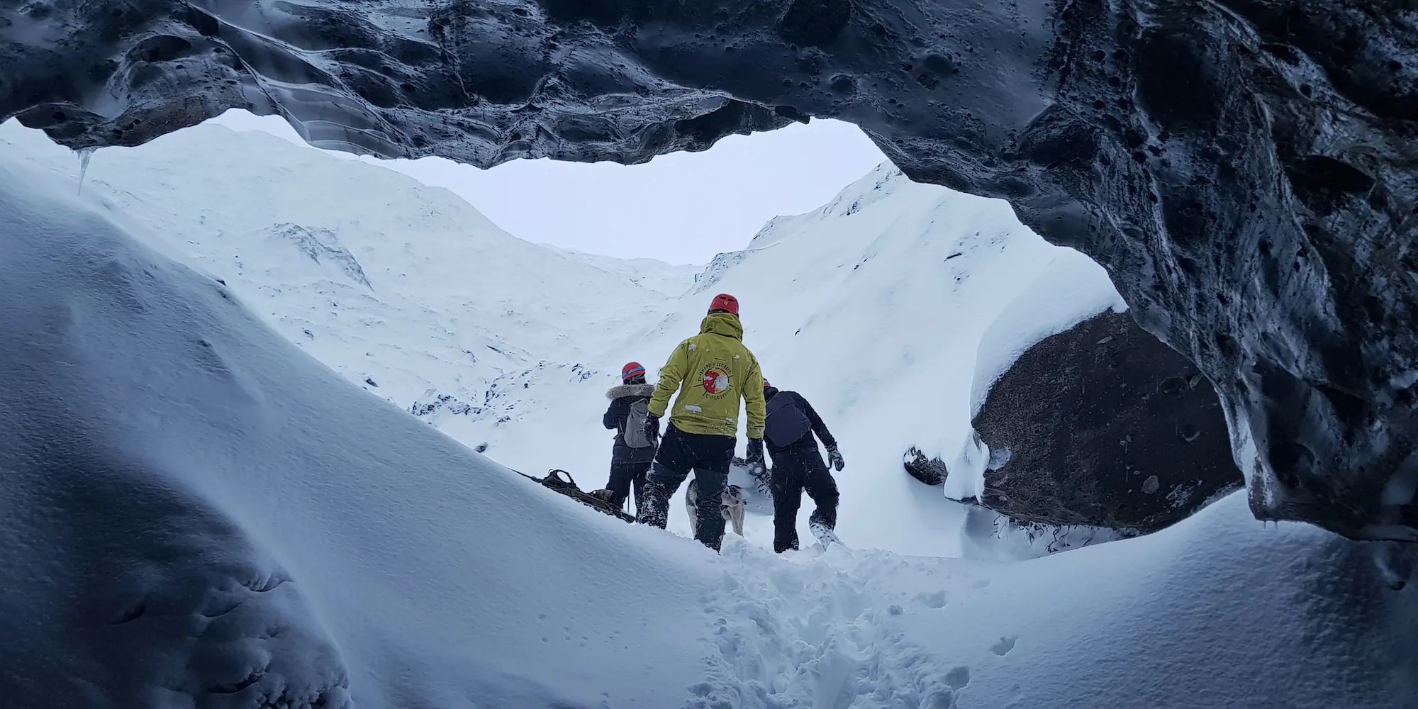 Tourists silhouetted in the mouth of a glacial ice cave in Svalbard, Norway.