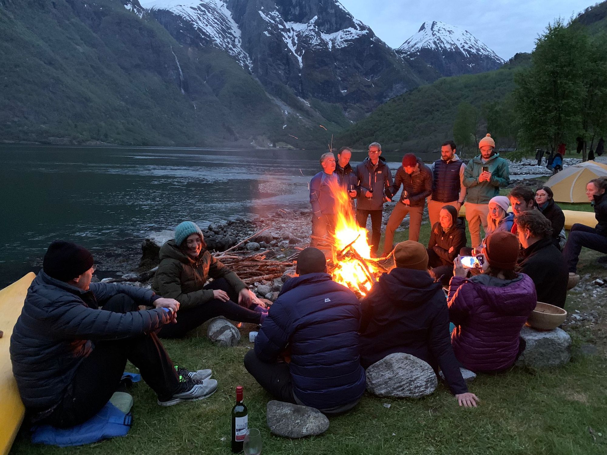 A kayaking group relaxing around the campfire of the Norwegian fjords.