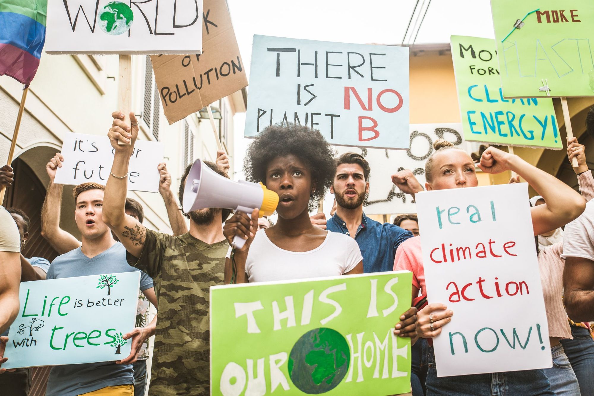 A climate change protest. Protesters of different races hold signs saying 'There is No Planet B' and 'Real Climate Action Now'