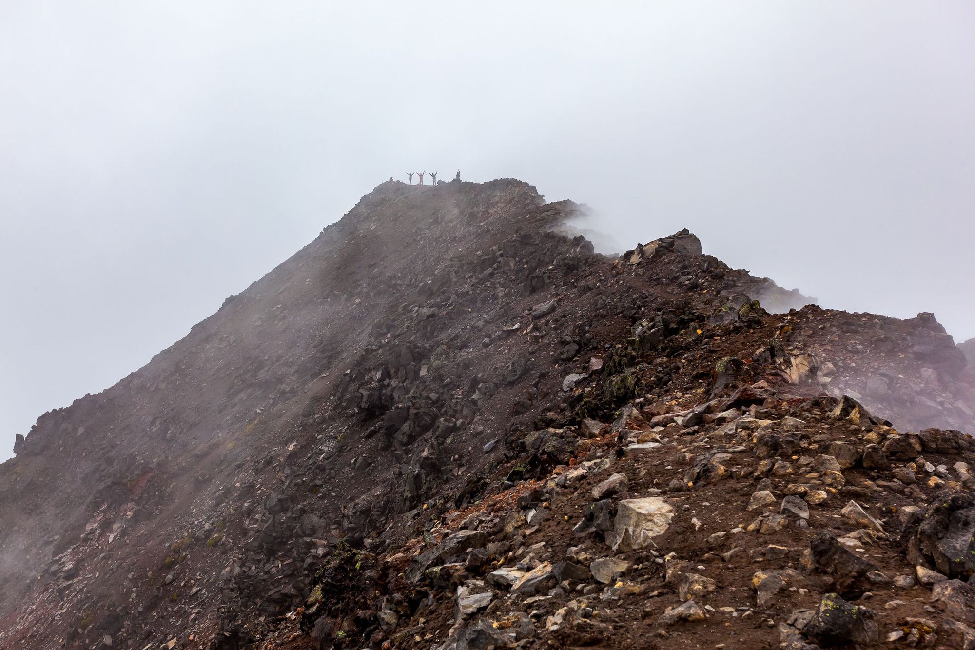 Hikers pose on the fog-shrouded summit of Corazón Volcano, in Ecuador.