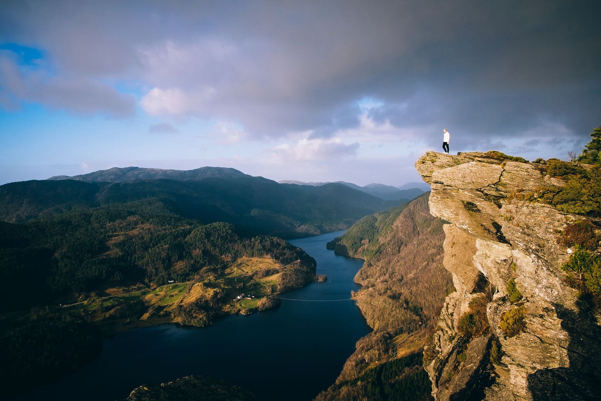 A man stands on top of viewpoint Himakånå, looking out over the Norwegian Fjords