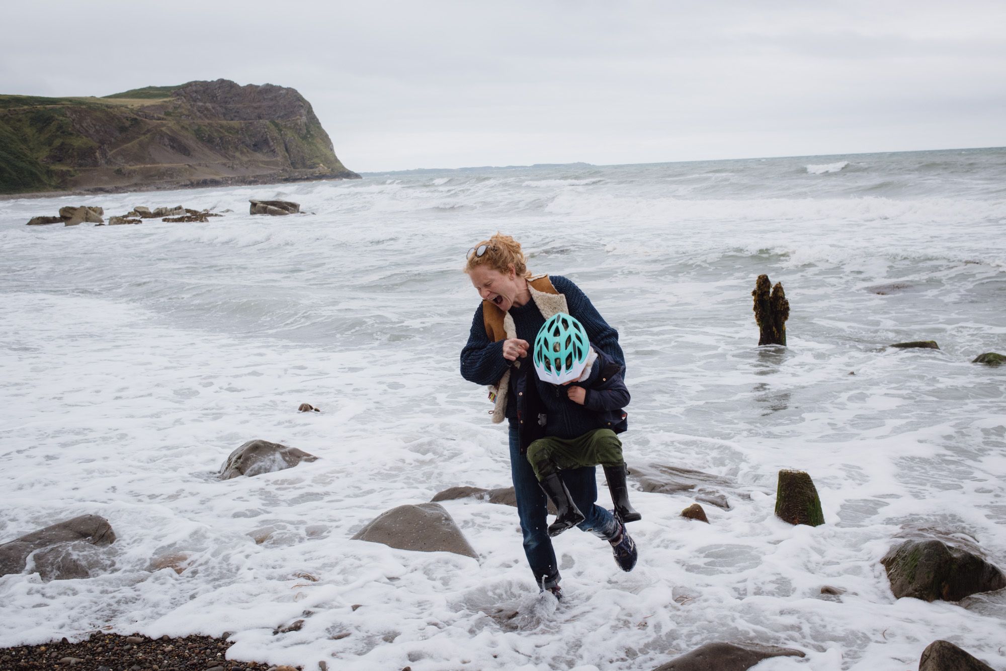 A woman plays in the ocean with her young child.