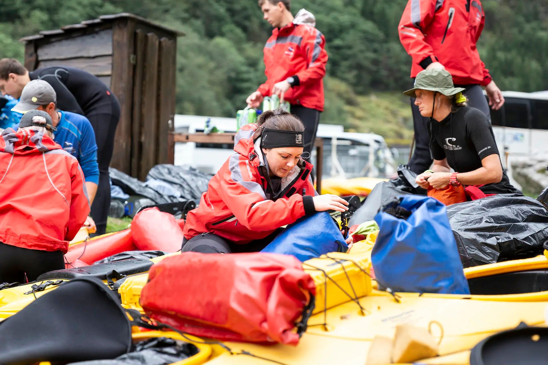 A tour group packing up their kayaks - in the foreground a woman is packing a dry bag