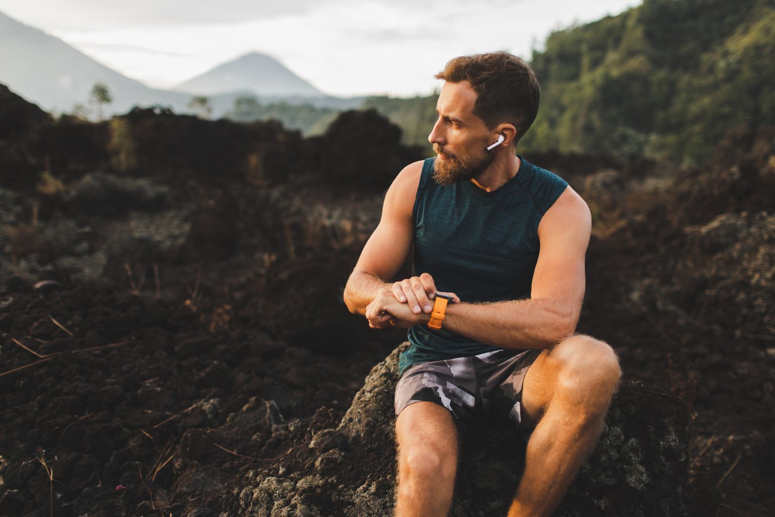 A trail runner sets his watch before running off into the mountains