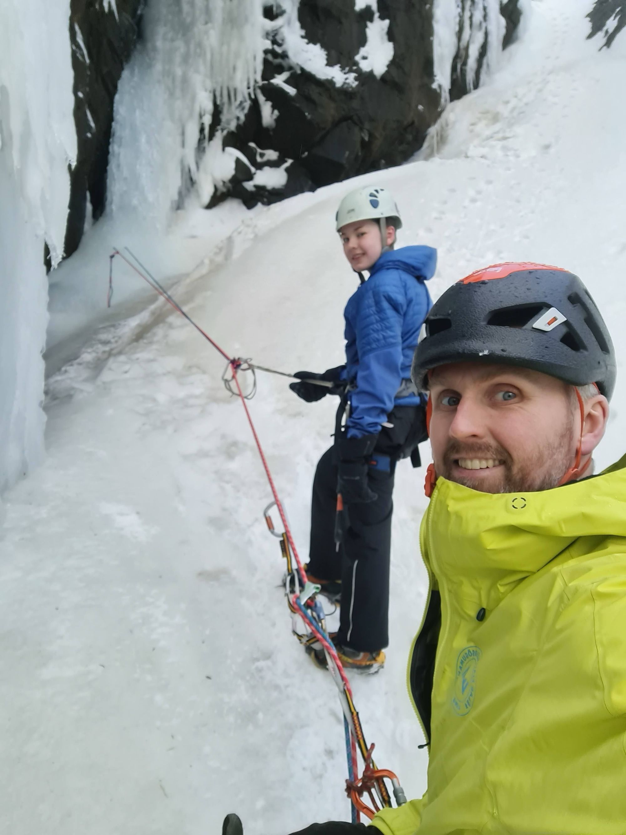 A man and a teenager roped up and ice climbing in Iceland