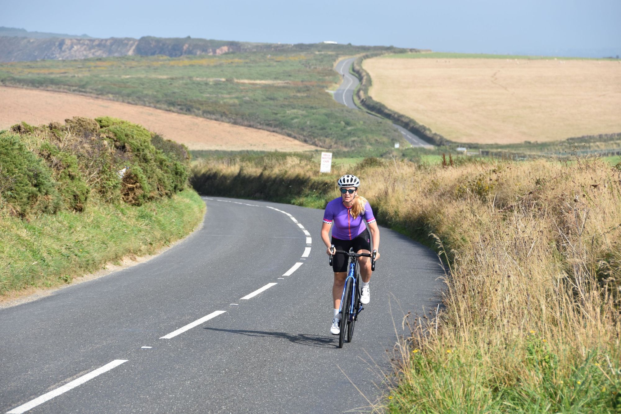 A woman cyclist riding on a country road in Cornwall