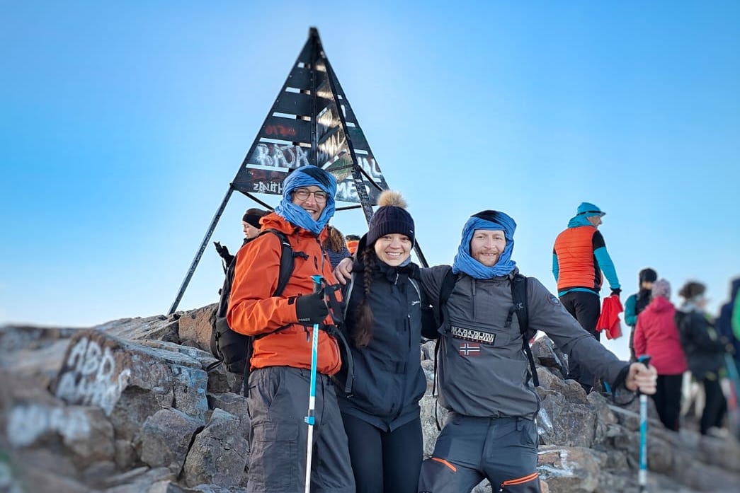 Three hikers pose at the top of Toubkal