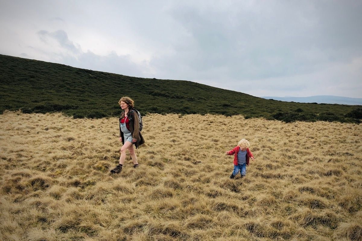 A pregnant woman and her child walking across a field.