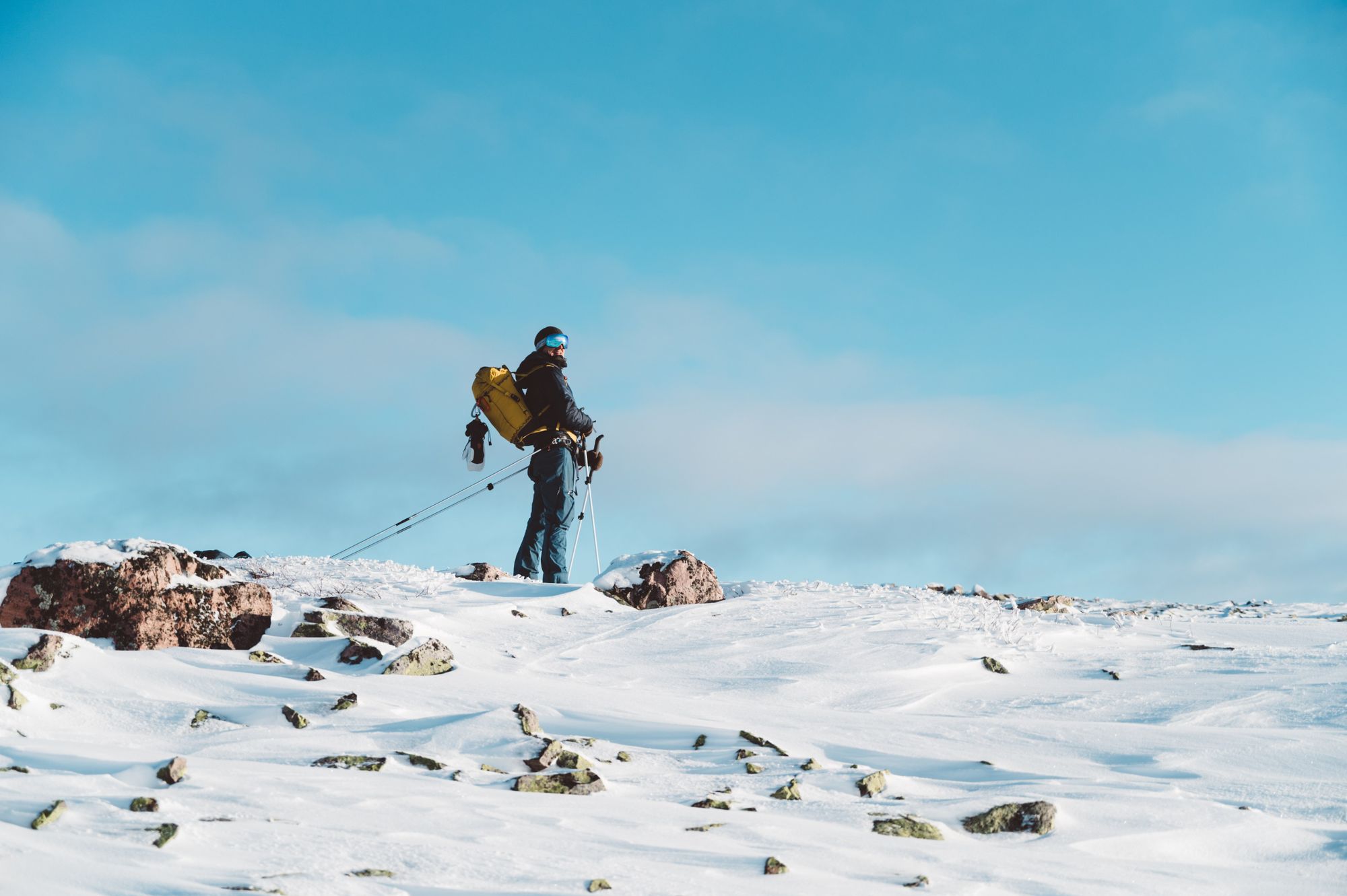 A skier looks at the camera from on top of a snowy ridge. Photo: Do the North