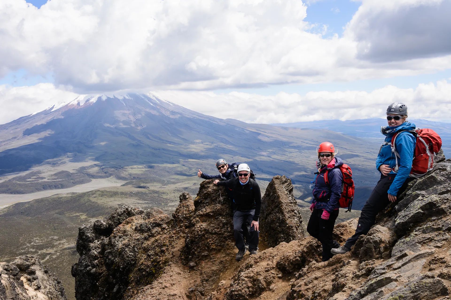 Hikers pose on the summit of  Rumiñahui, Ecaudor. Cotopaxi can be seen in the background.
