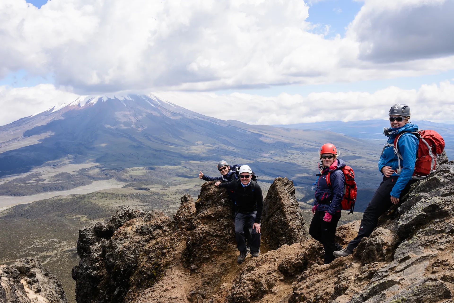 Hikers pose on the summit of Rumiñahui, Ecaudor. Cotopaxi can be seen in the background.