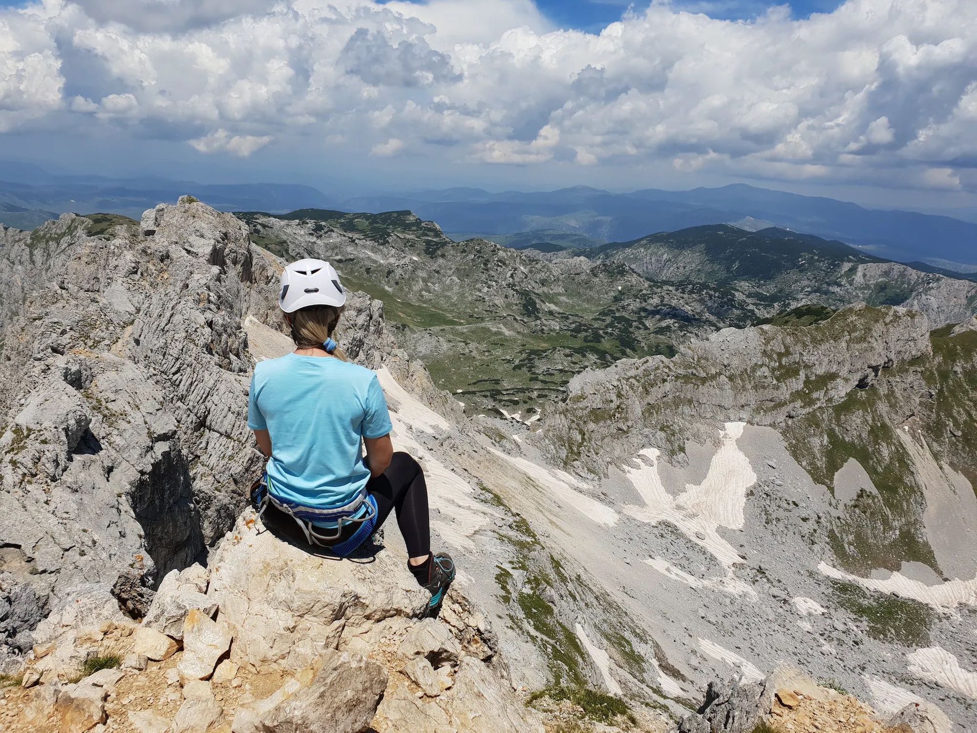 A woman mountaineer sits at the top of the Bobotov Kuk summit, Montenegro.