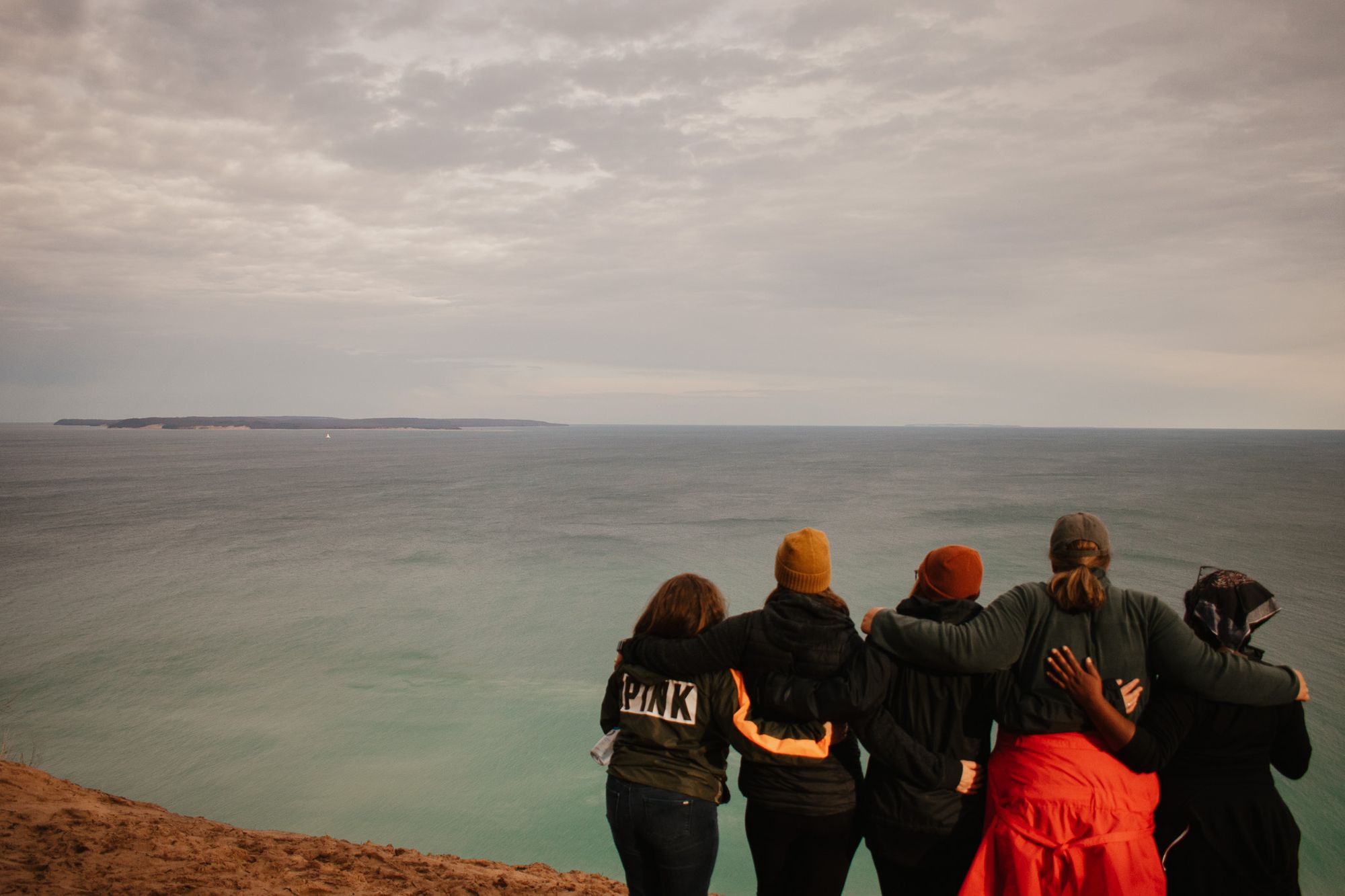 Four women pose in front of the ocean.