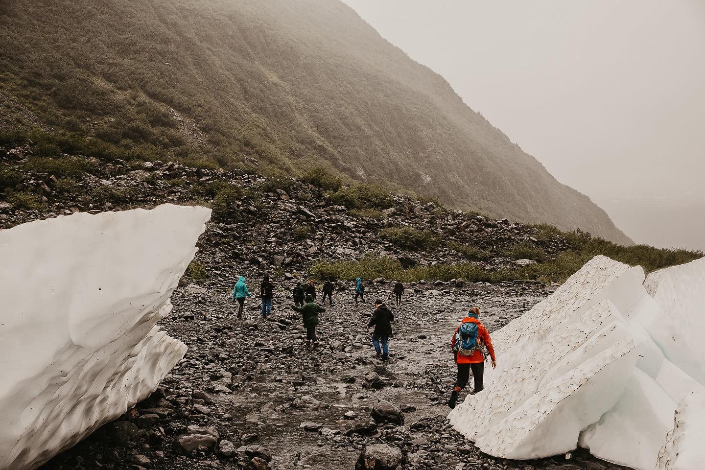 Hikers along the Byron Glacier Hike trail in Alaska, on a cloudy day.