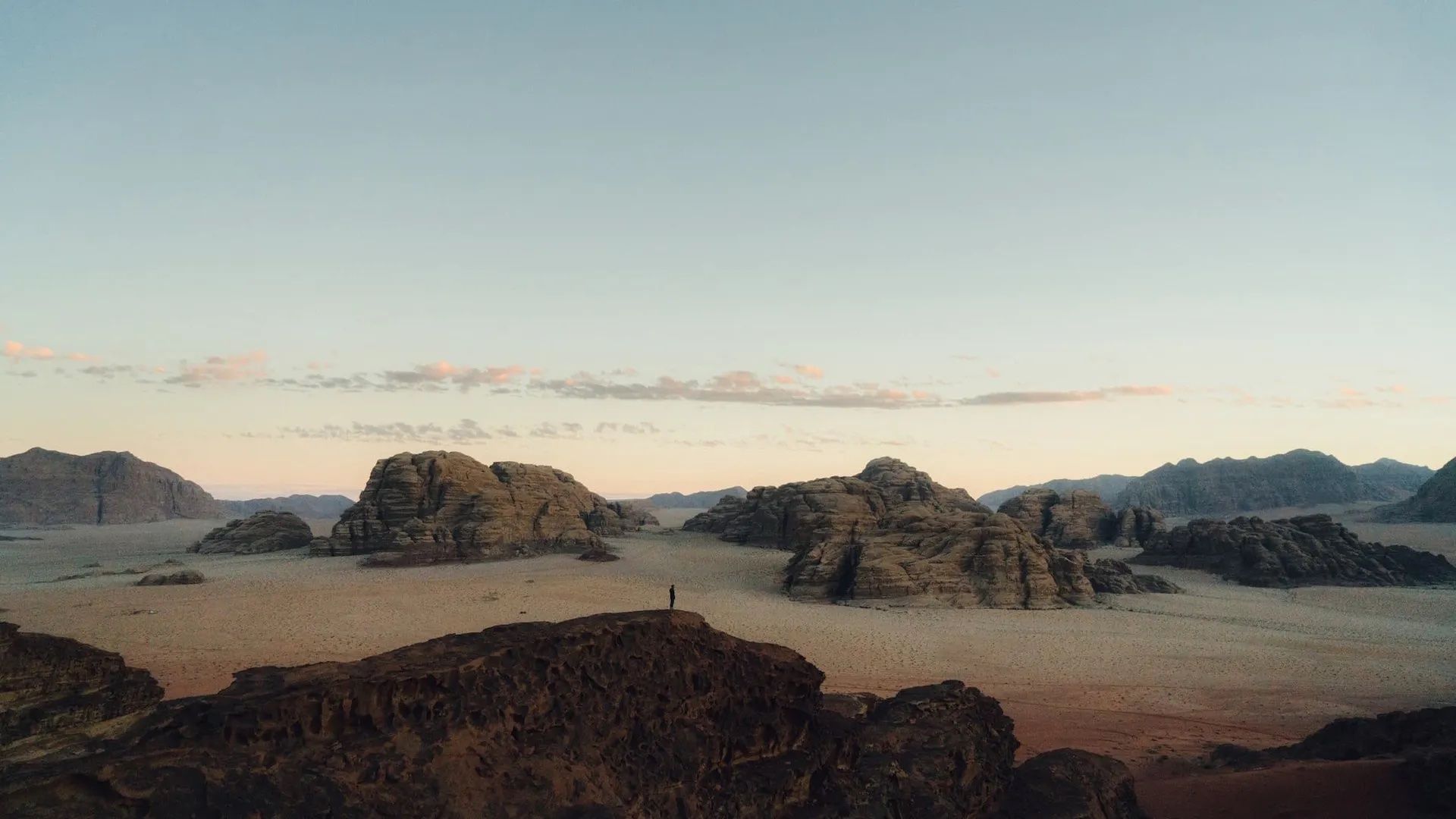 A man stands on a rock in the Wadi Rum Desert, Jordan