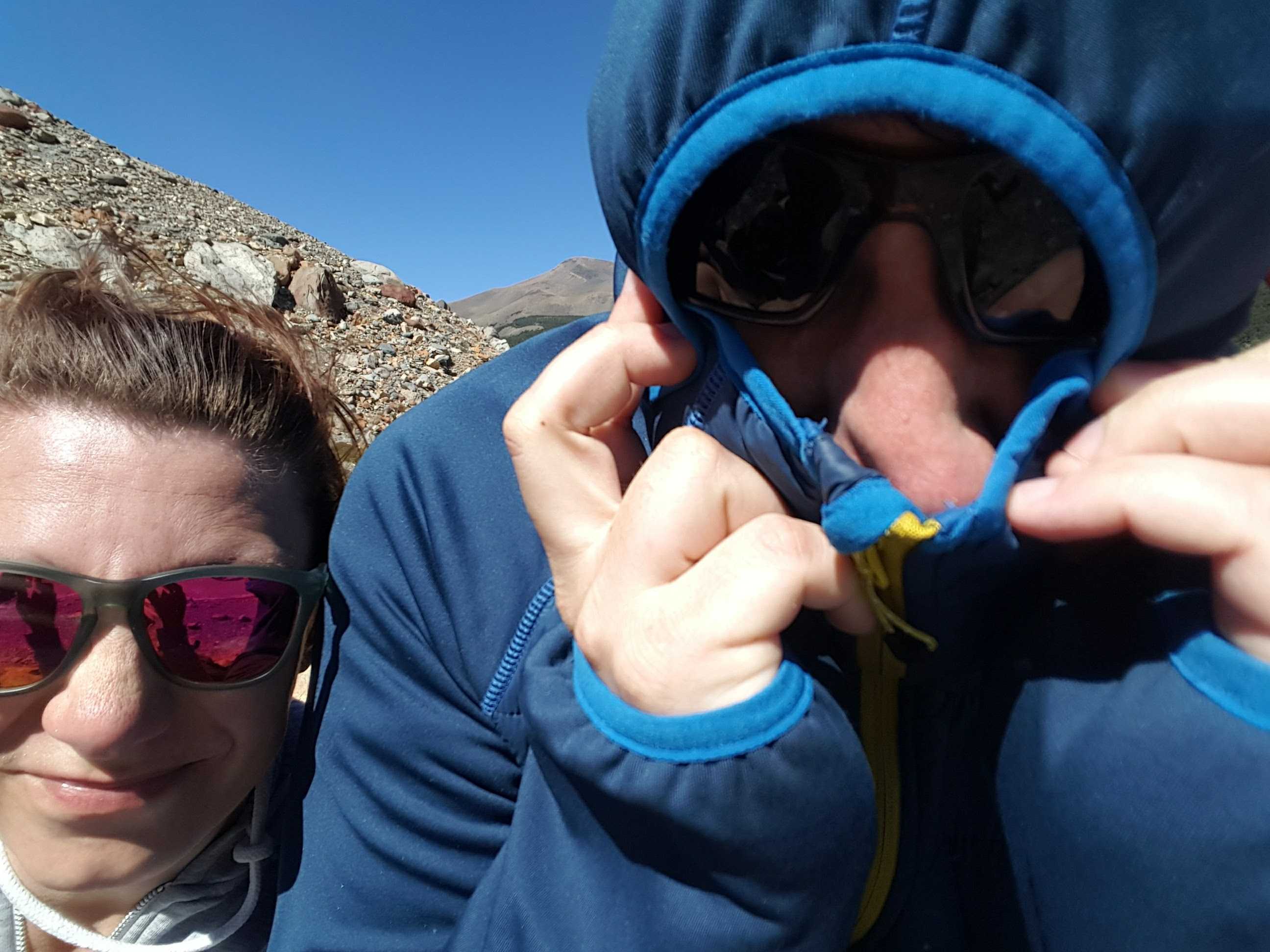 Two hikers shielding their faces from the wind in Patagonia.