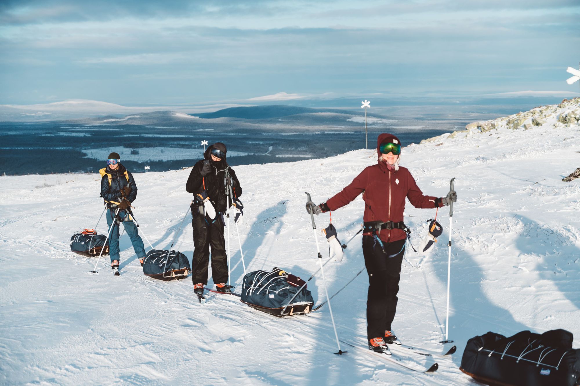 Three adventurers pulling a sled while Nordic skiing in scenic Sweden. Photo: Do The North