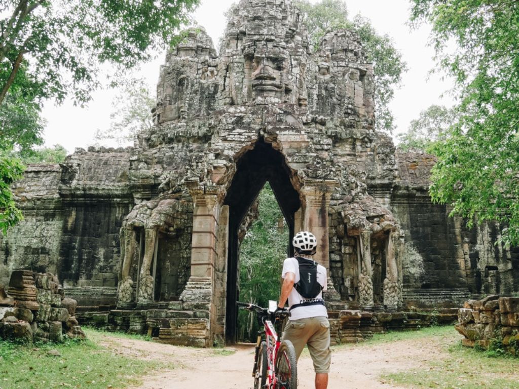 A cyclist stands in front of one of the entrances to mighty Angkor Wat, in Cambodia