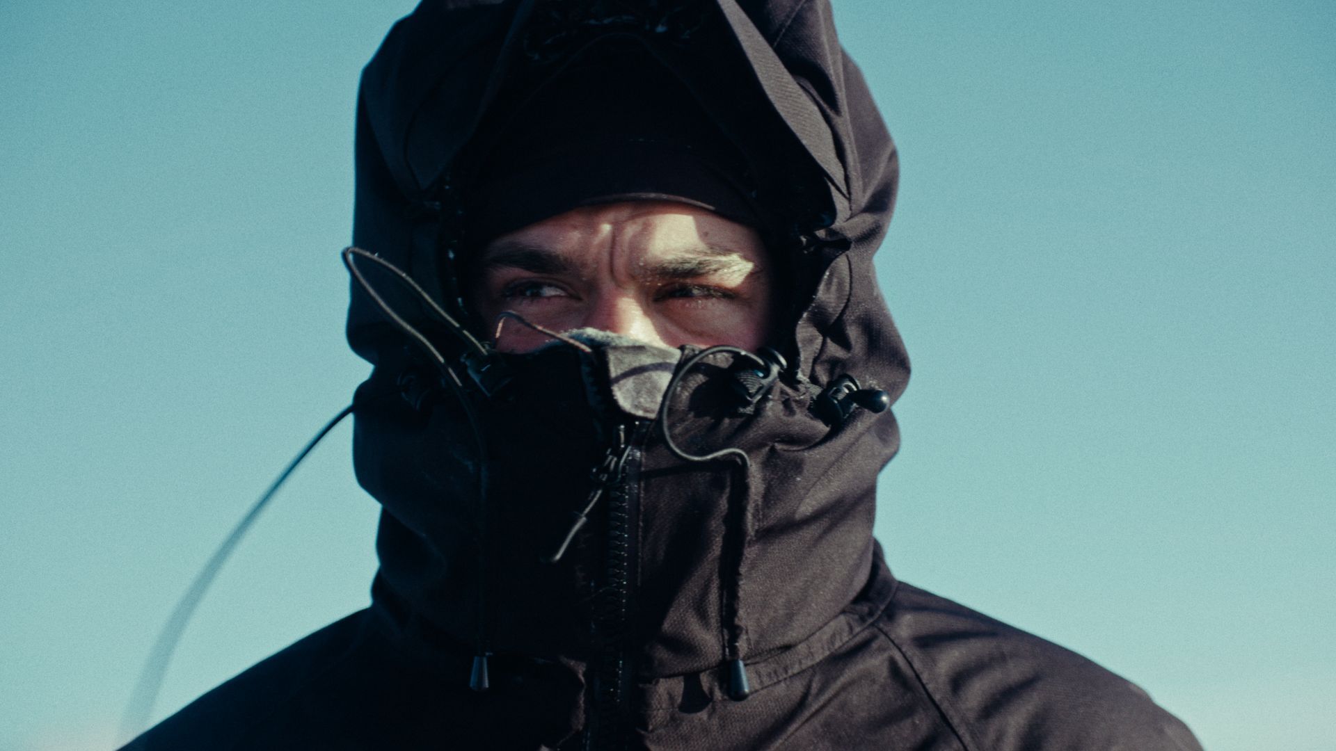 A close up of a dog sledder with his hood up.