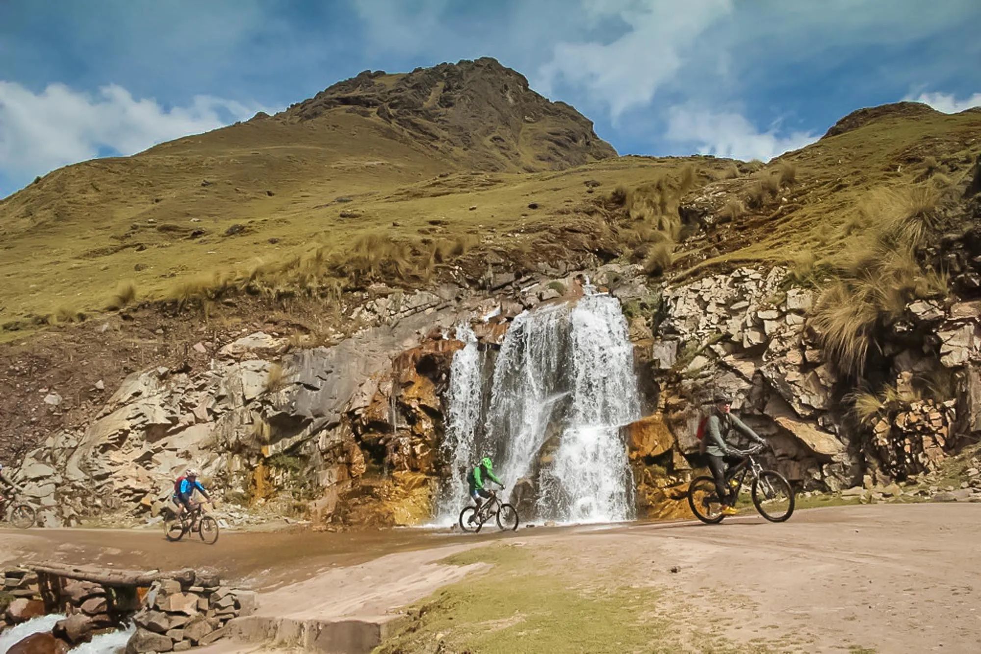 Cyclists passing a waterfall in the Peruvian Andes.