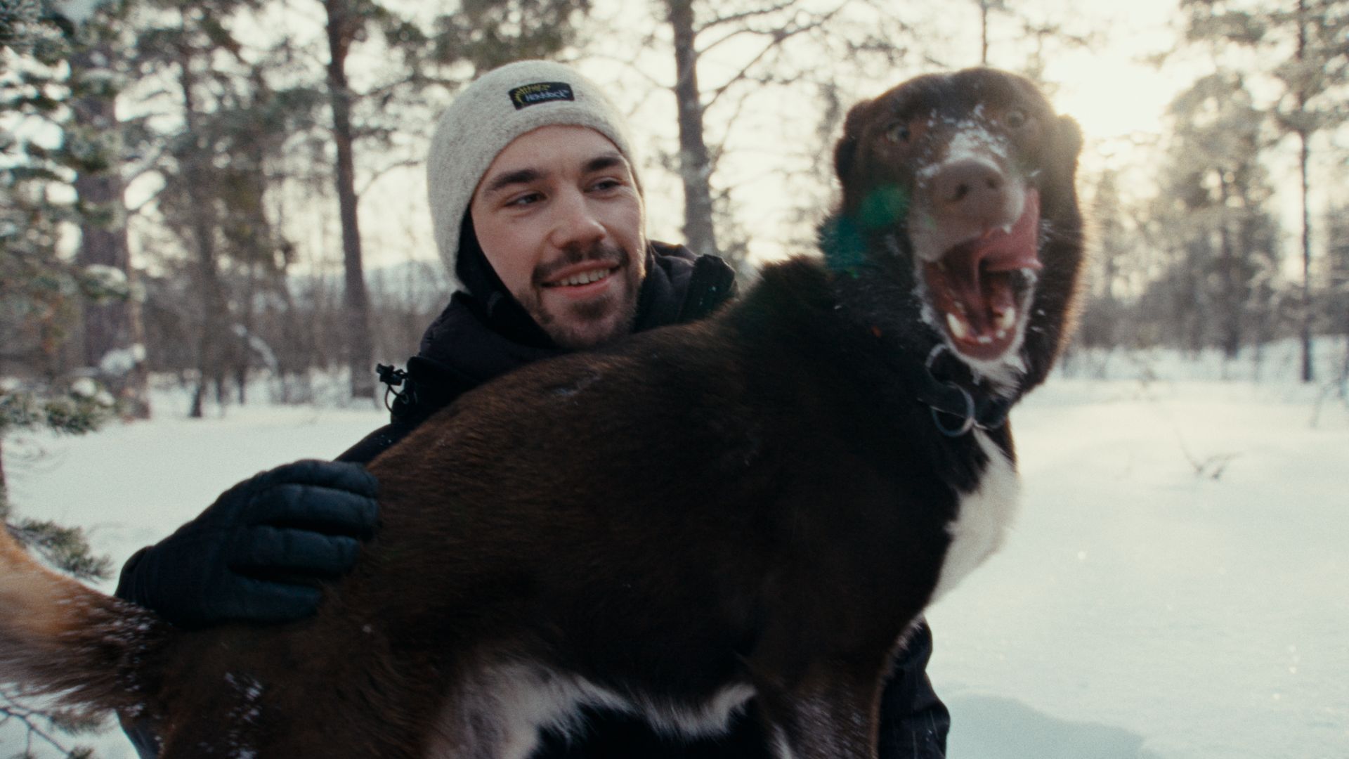 A man playing with his husky dog in the snow.