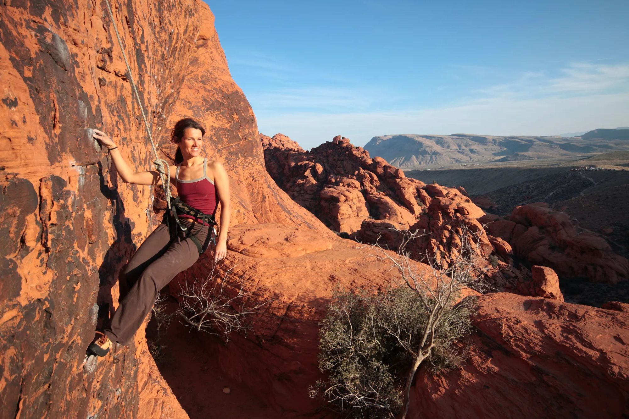 A female hiker poses on the red cliff face of the Todgha Gorge in Morocco.