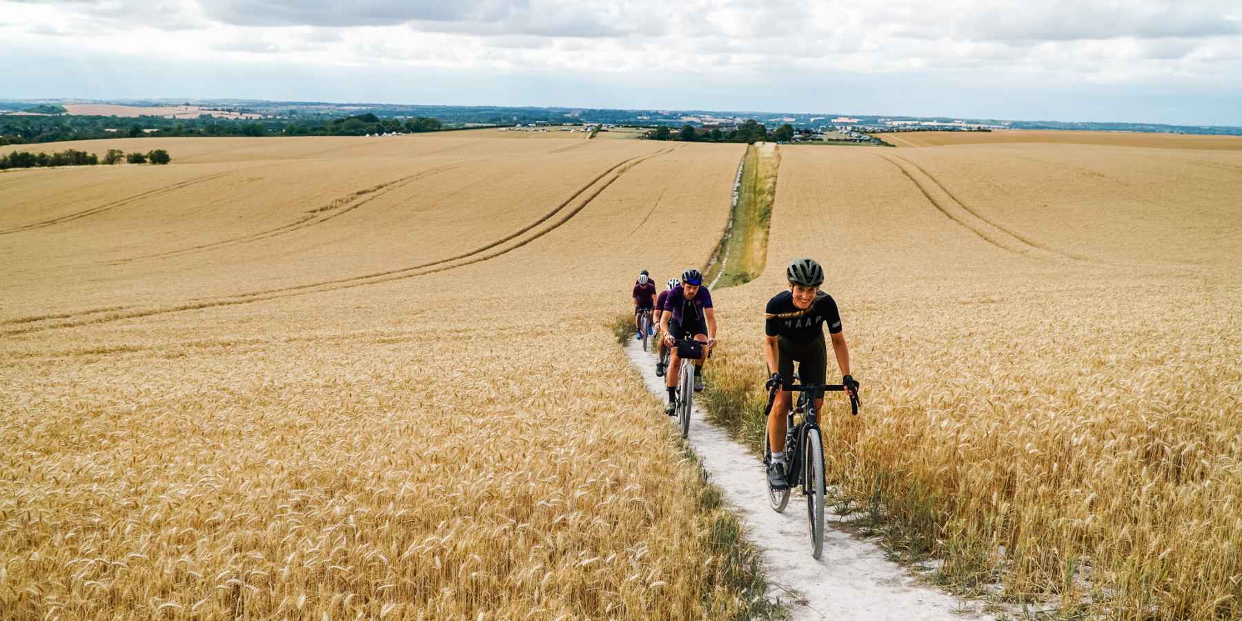 Cyclists on a gravel track going through a wheat field