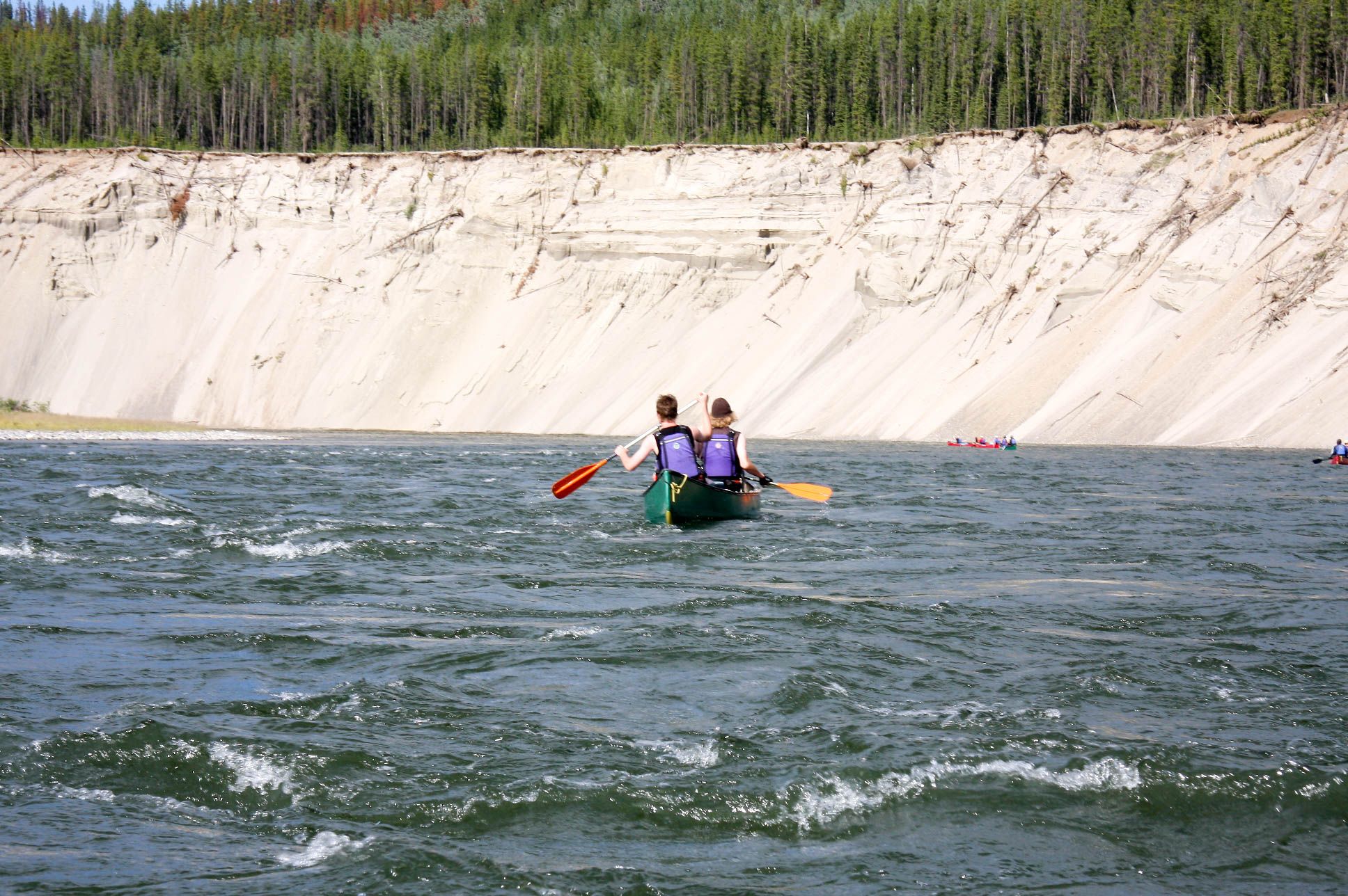 A group of canoeists on choppy waters in the Yukon River.