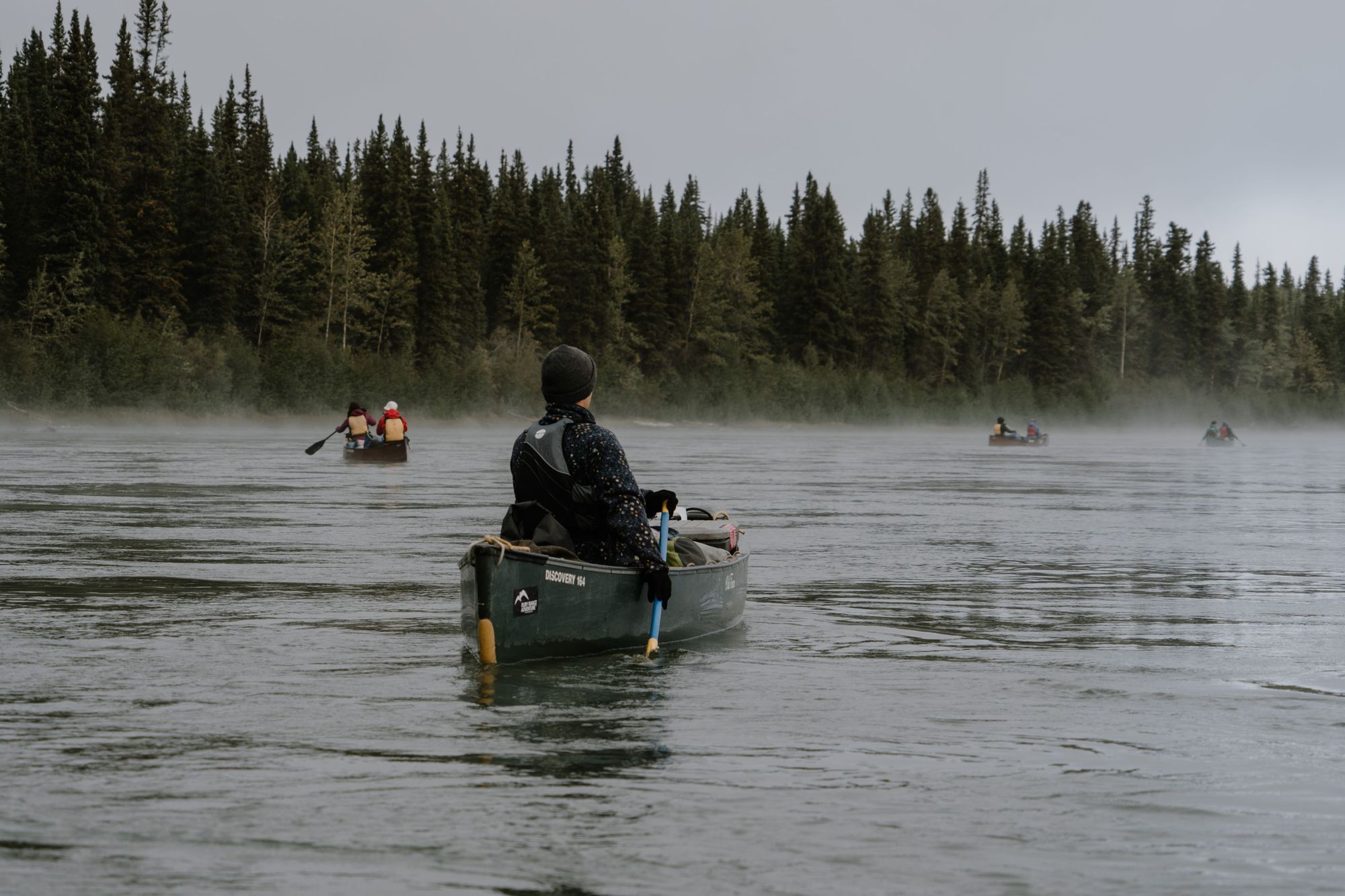 A group of canoeists on the Yukon River on a misty morning.